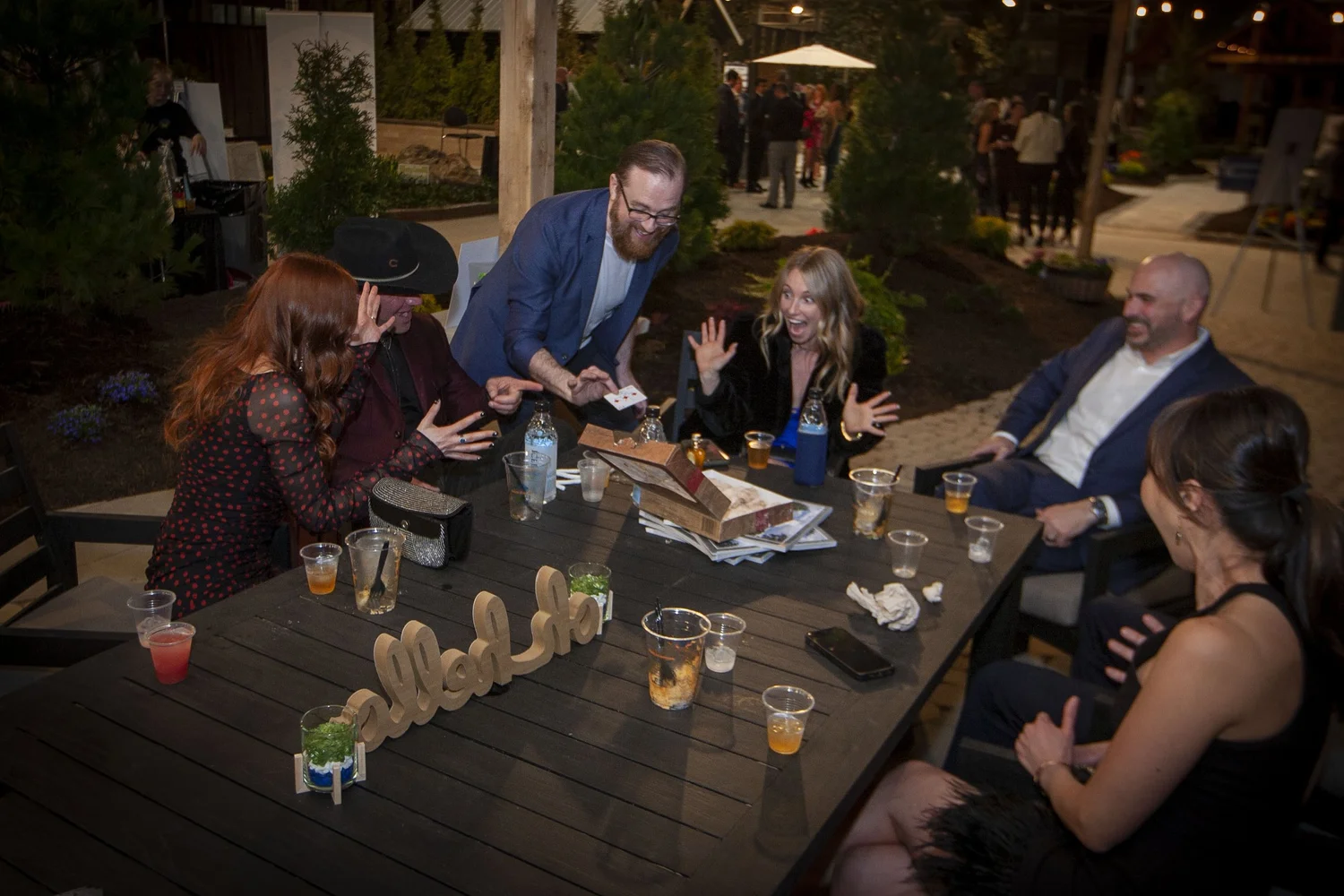 Guests laughing around an outdoor table during a magic set