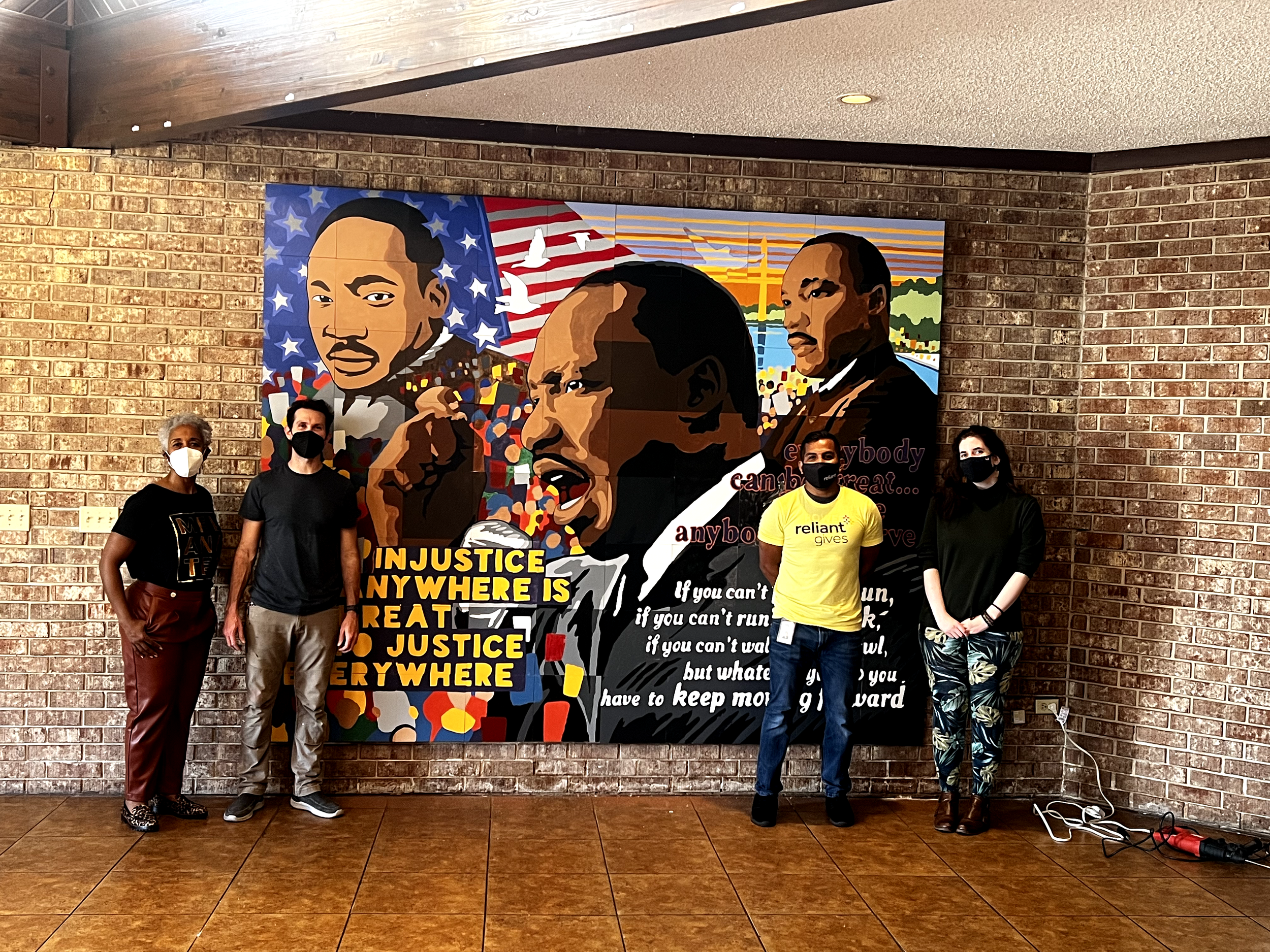 Volunteers take pictures in front of the MLK mural.