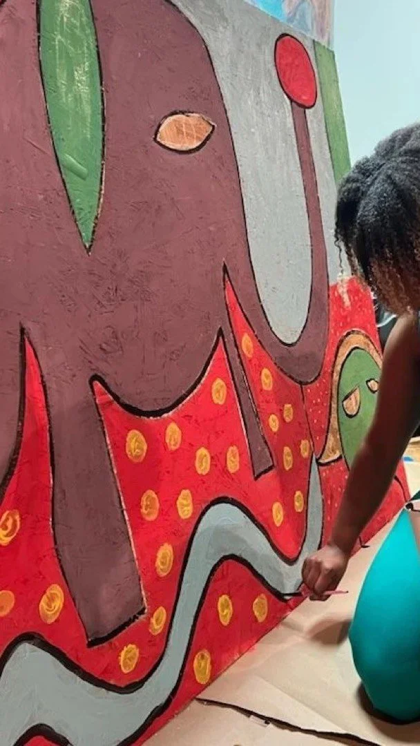 Person painting abstract colorful mural with bold patterns and shapes.