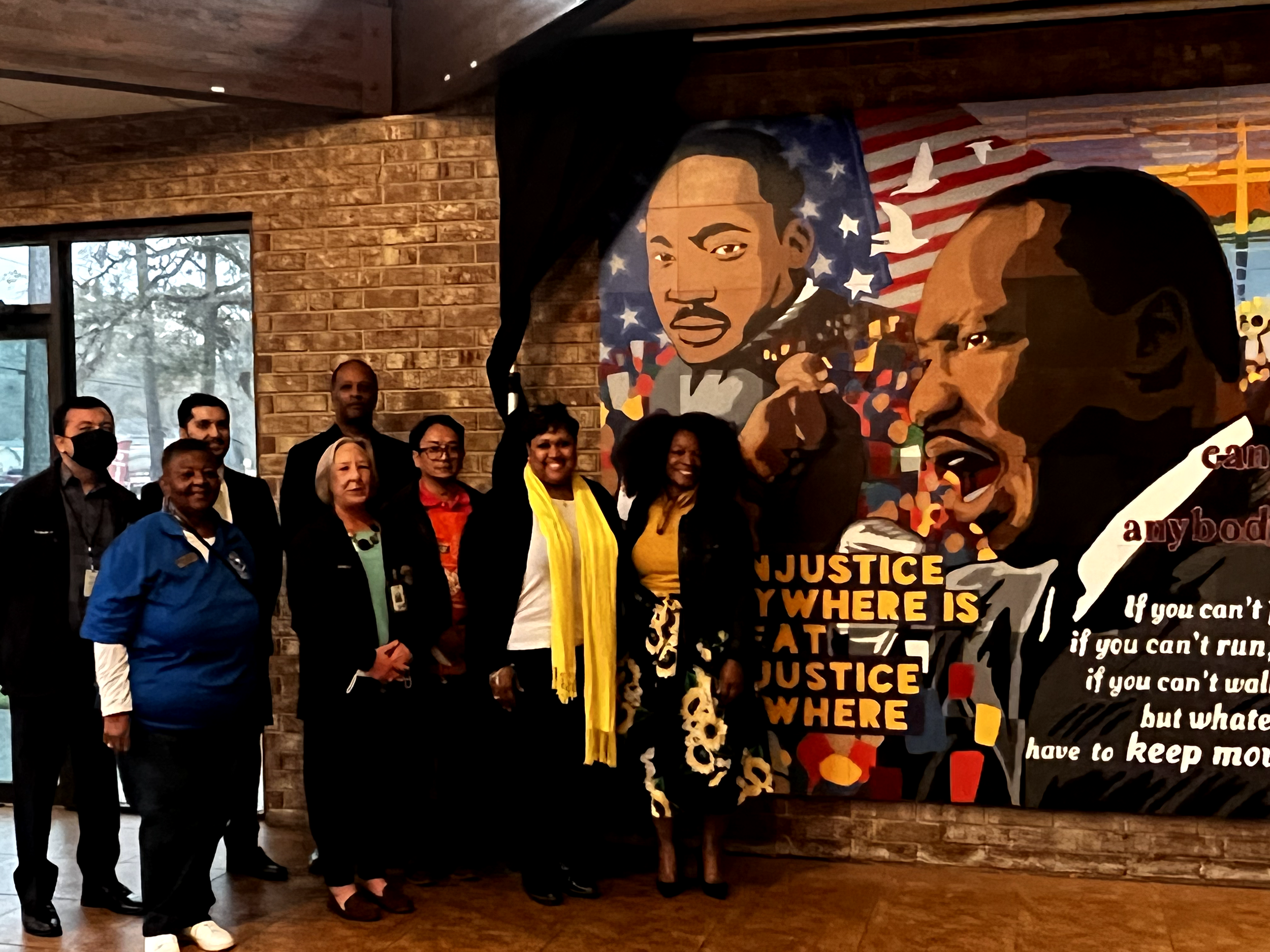 volunteers and Michelle Bonton takes a picture with the MLK mural. 