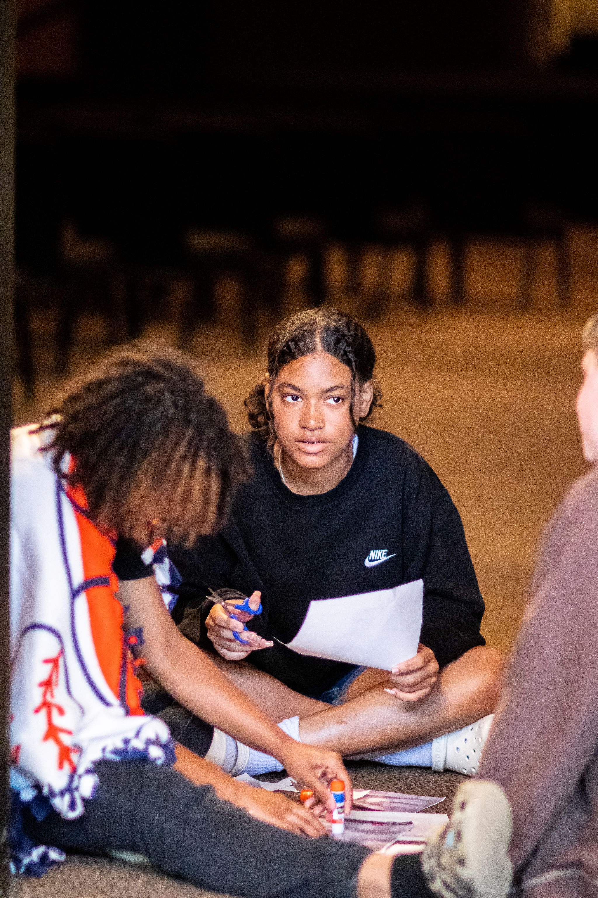 Girls engaging in collage making on theater floor. 