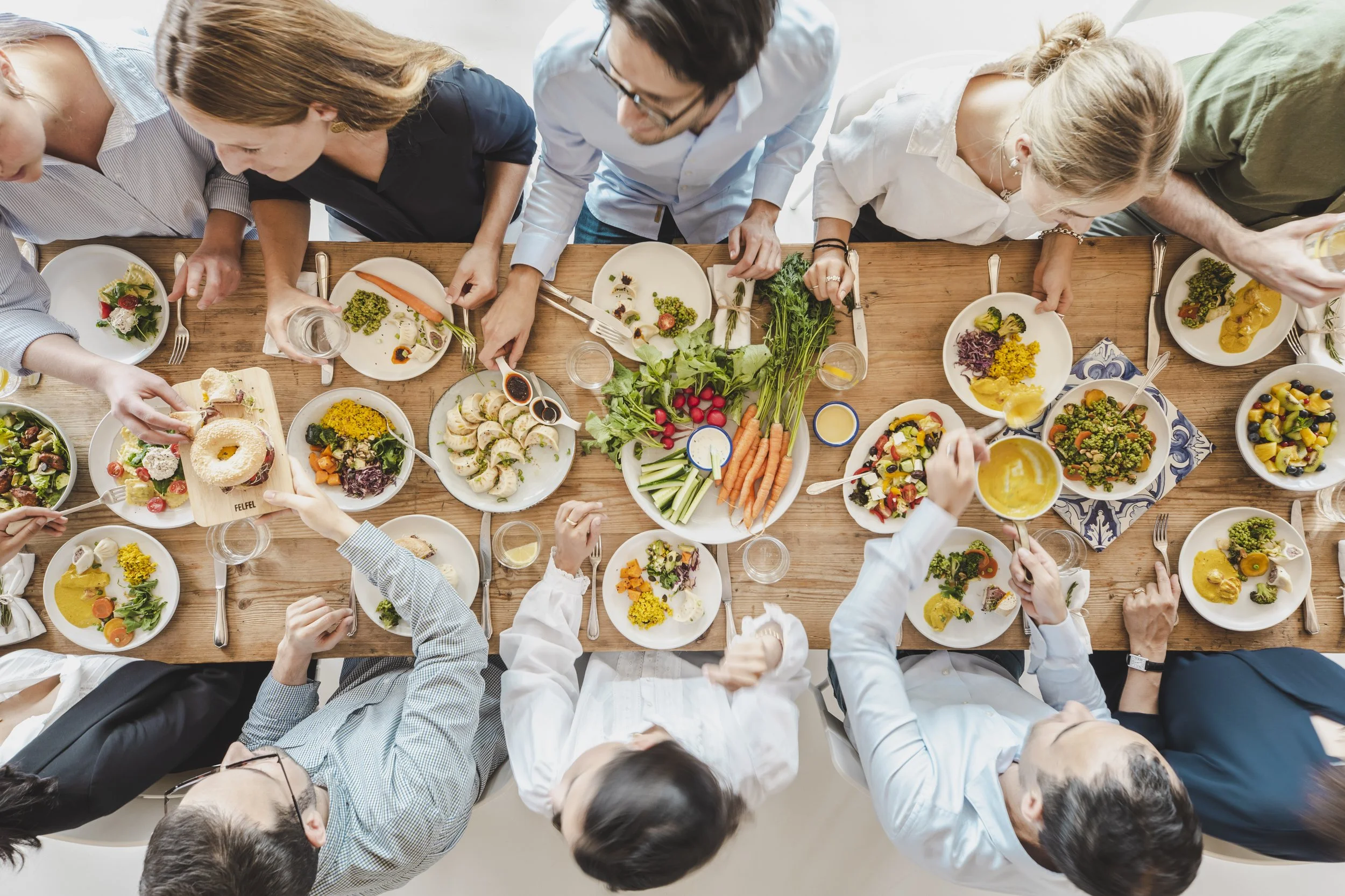 Team isst gemeinsam frische FELFEL Gerichte am Tisch im Büro