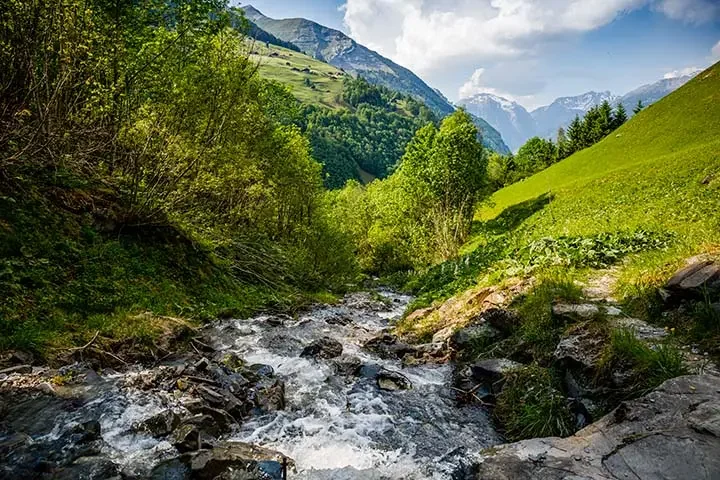 Runder Steinbrunnen gefüllt mit grün-gelben Elmer Citro Flaschen in Elm, Glarus