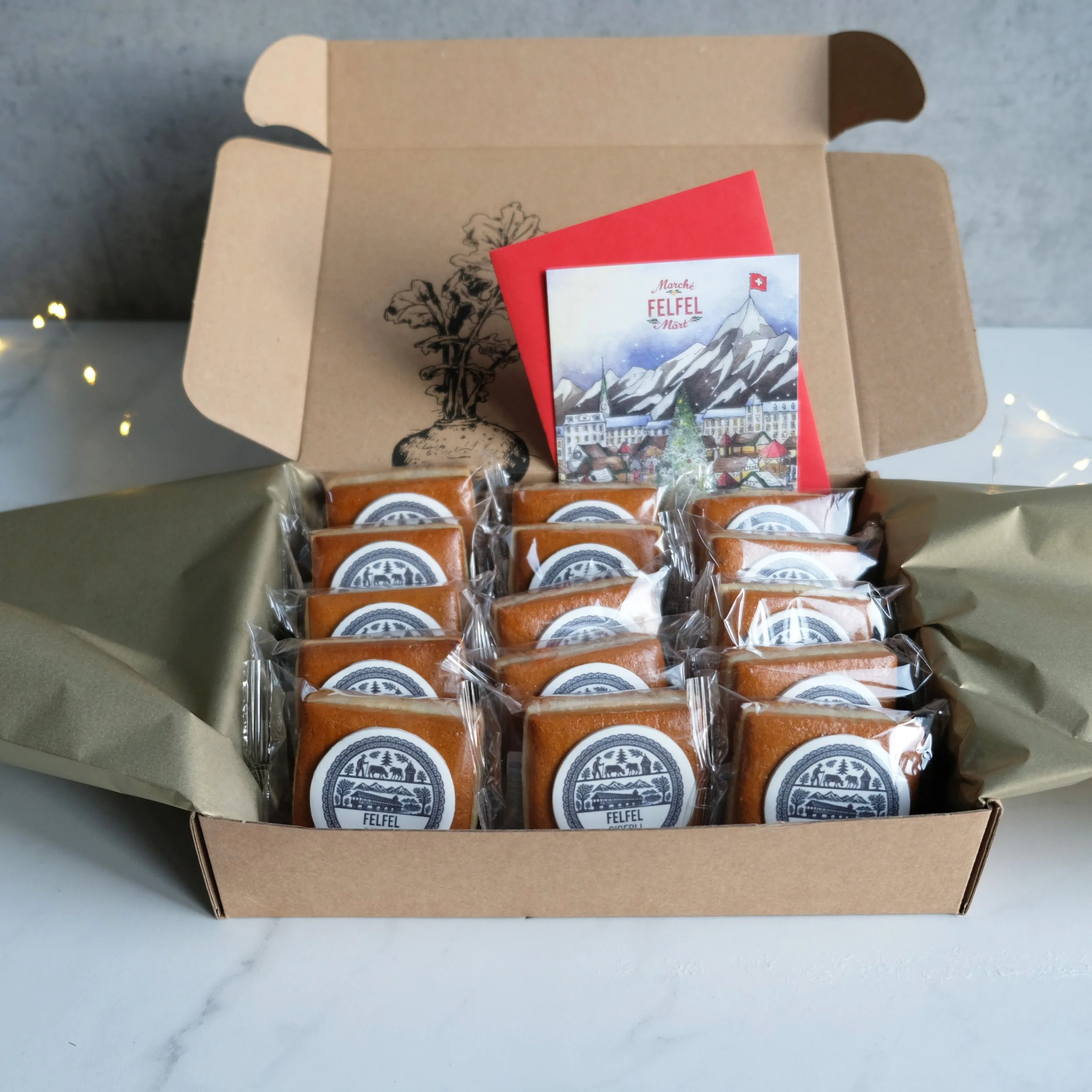 Offene FELFEL Geschenkbox gefüllt mit einzeln verpackten Biberli und einer Grusskarte.