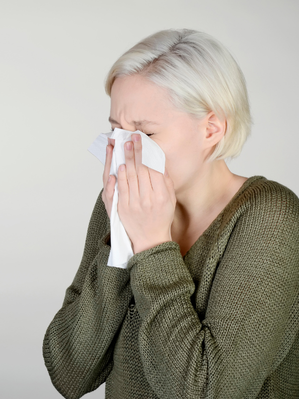 image of woman sneezing into a tissue from hayfever and allergies