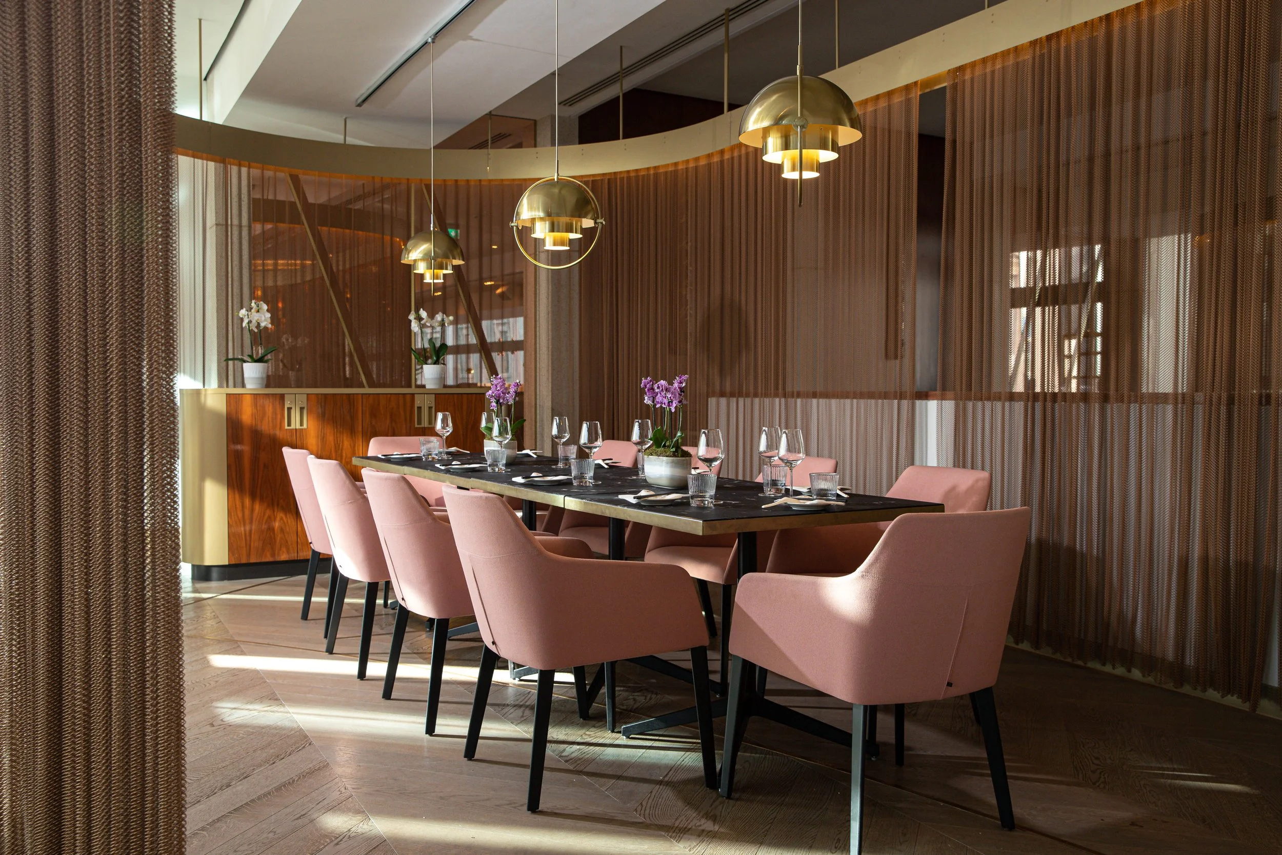 private dining room at din tai fung centre point, with elegant table settings, pink plush chairs and gold opulent lighting