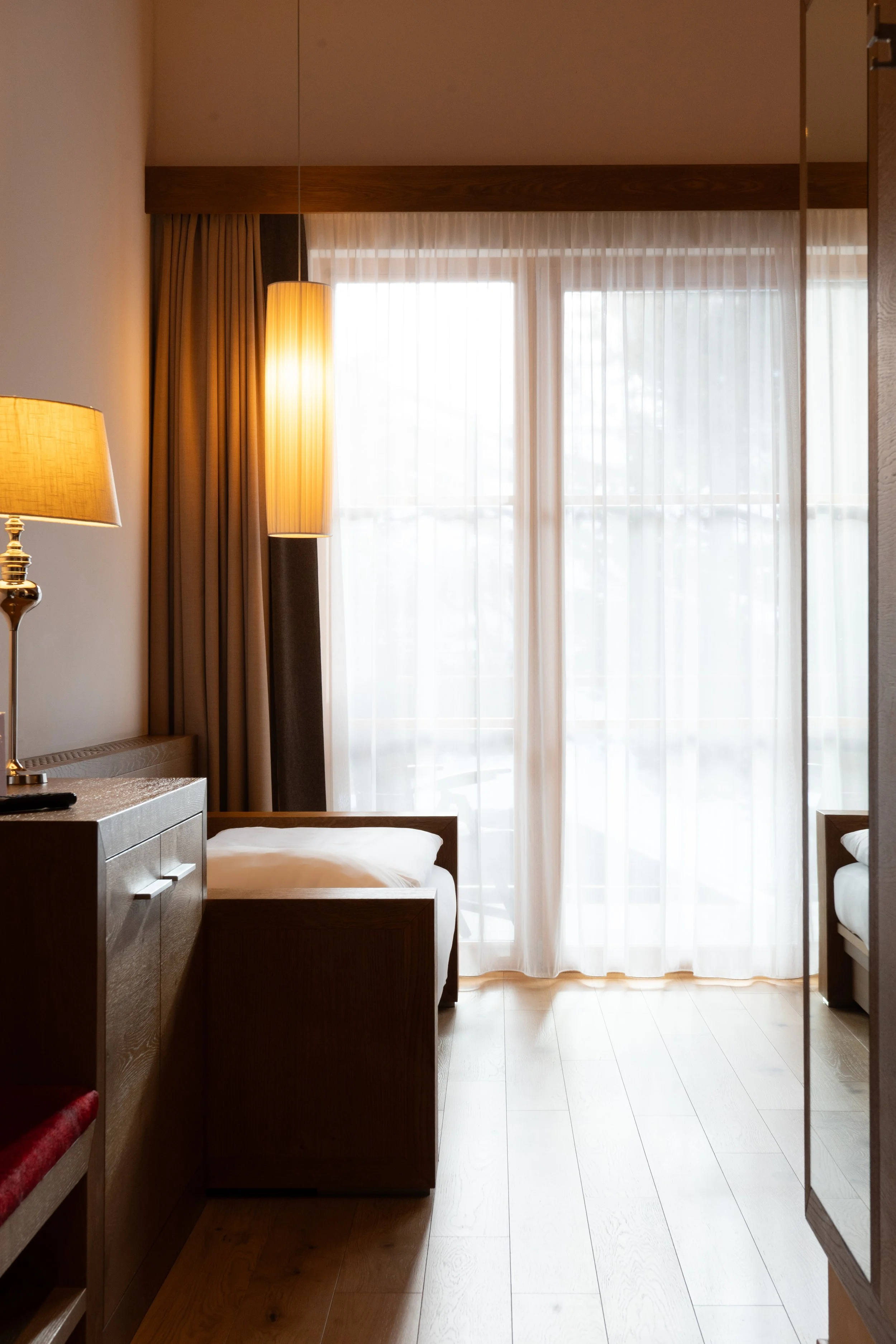 La Fradora Dolomites Wellness Hotel in Alta Badia, showcasing a bedroom with contrasting lighting and warm tones.