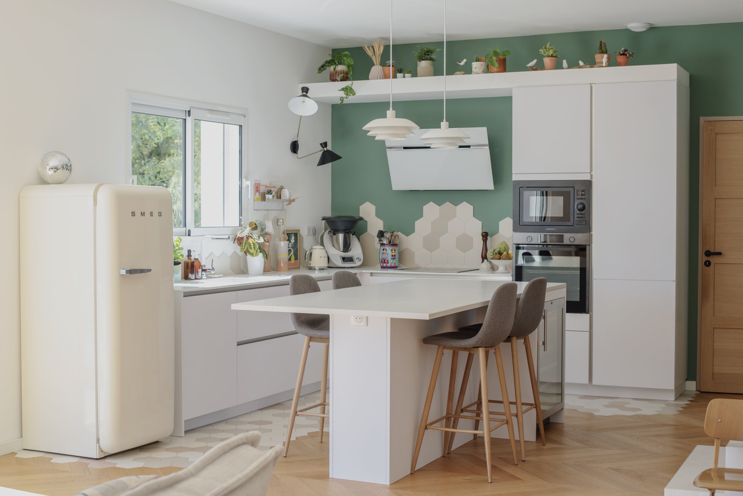 Photo d'une cuisine design blanche et mur vert. Plantes