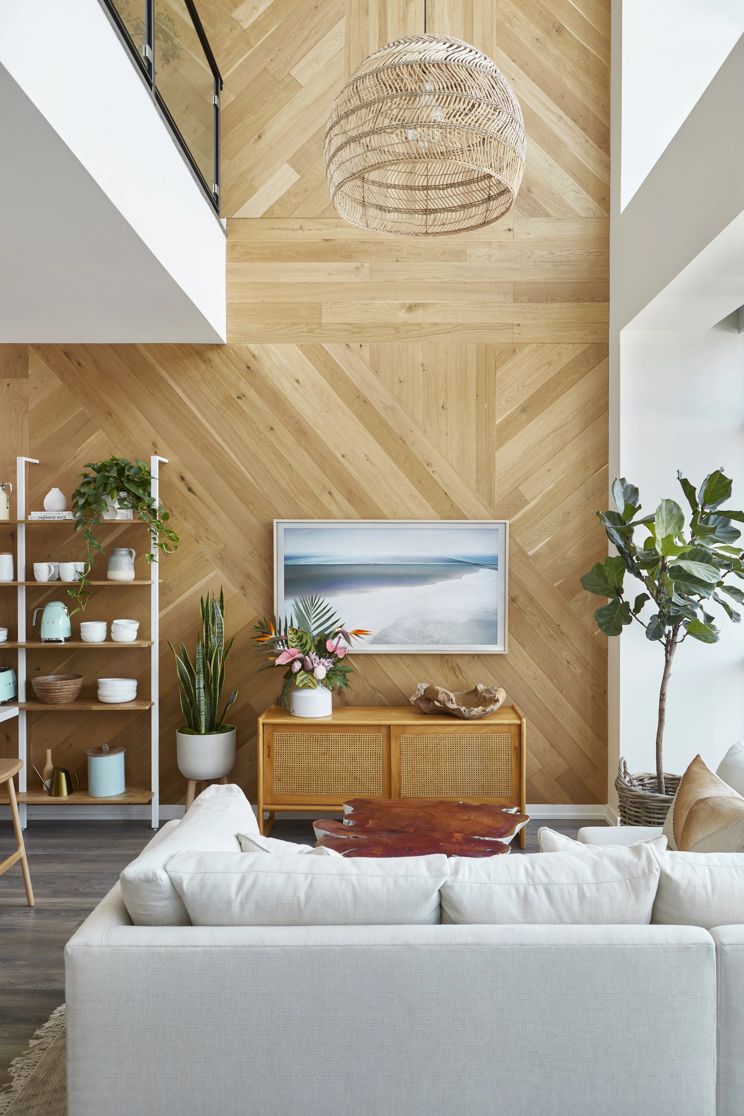 Living room with wood-paneled wall, potted plants, a white sofa, and decor items.
