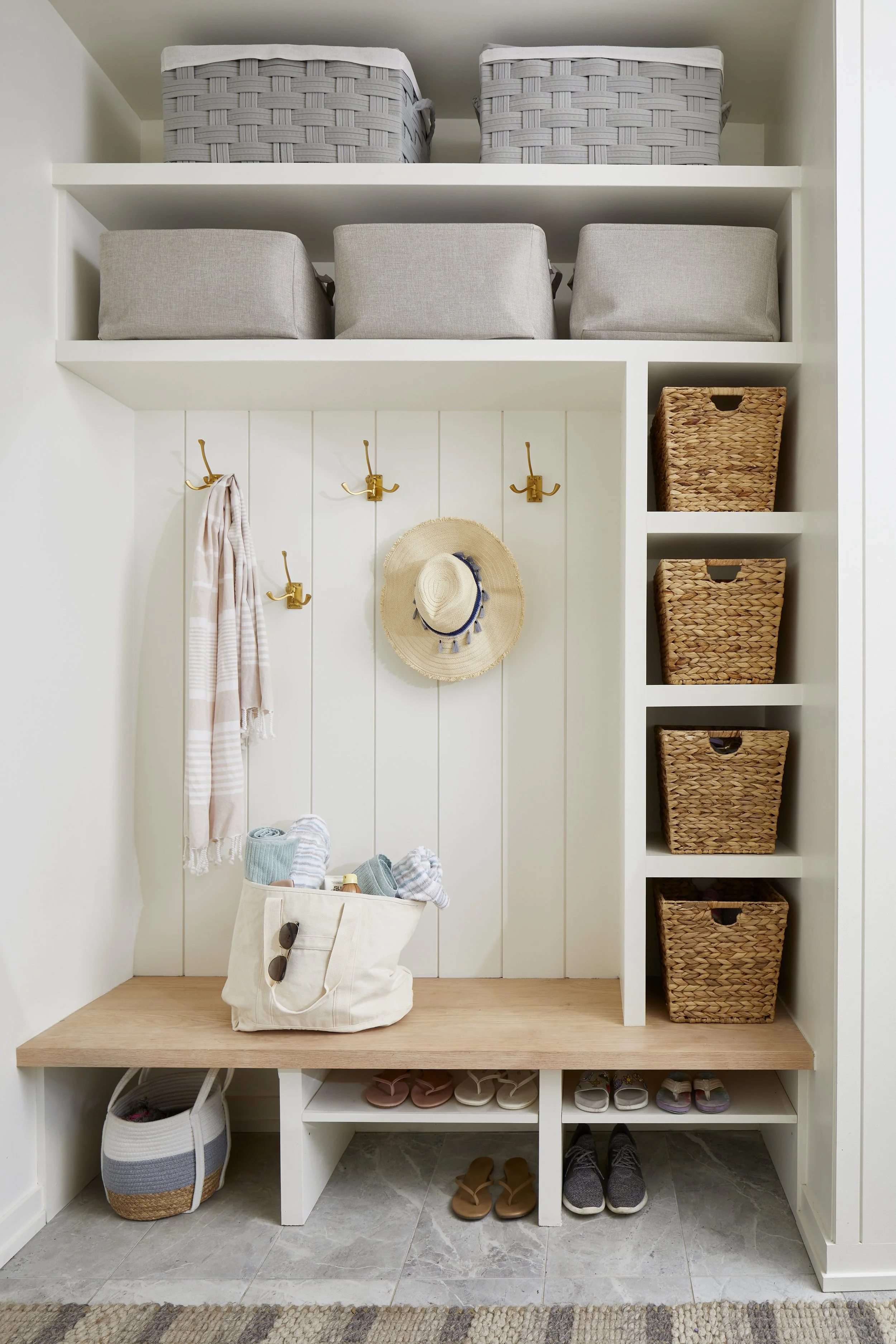 Closet with shelves, baskets, hooks, a hat, and shoes on the floor.