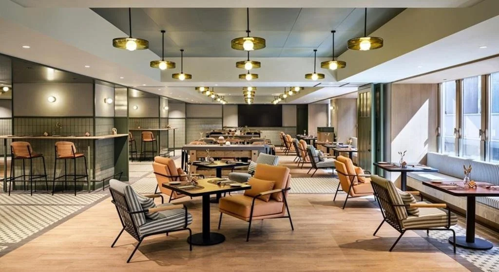 Salle à manger de restaurant élégante avec tables et chaises, lumière suspendue et fenêtres avec vue extérieure.