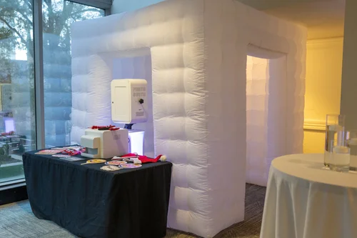 White inflatable photo booth set up in an event space with a props table