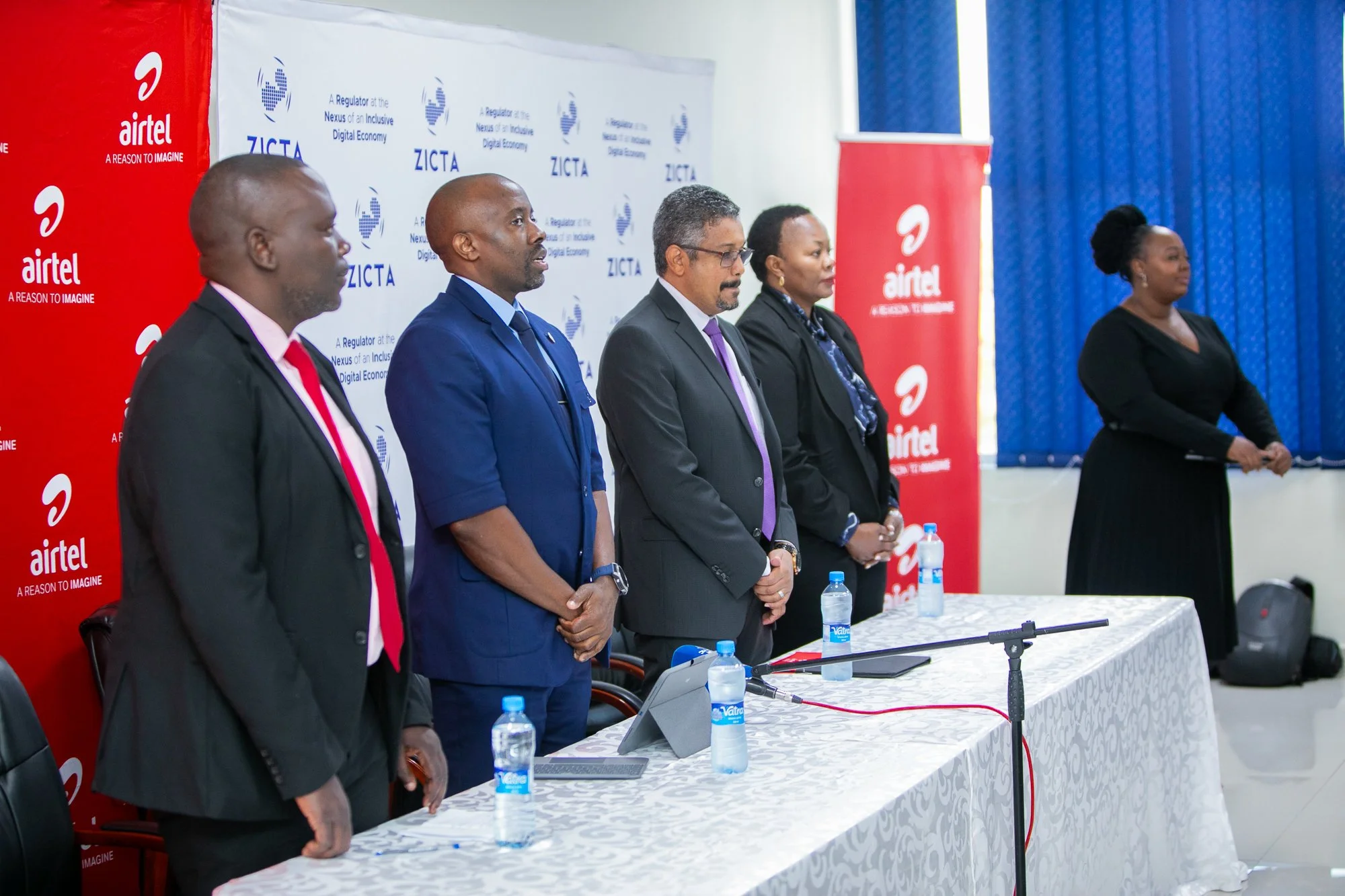 A group of five individuals standing behind a table at a formal event, with Airtel branding and a banner that reads "A Regulator at the Nexus of an Inclusive Digital Economy" in the background.