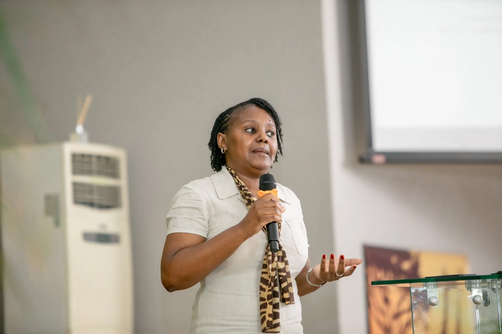 A woman with short hair holding a microphone in a presentation room.