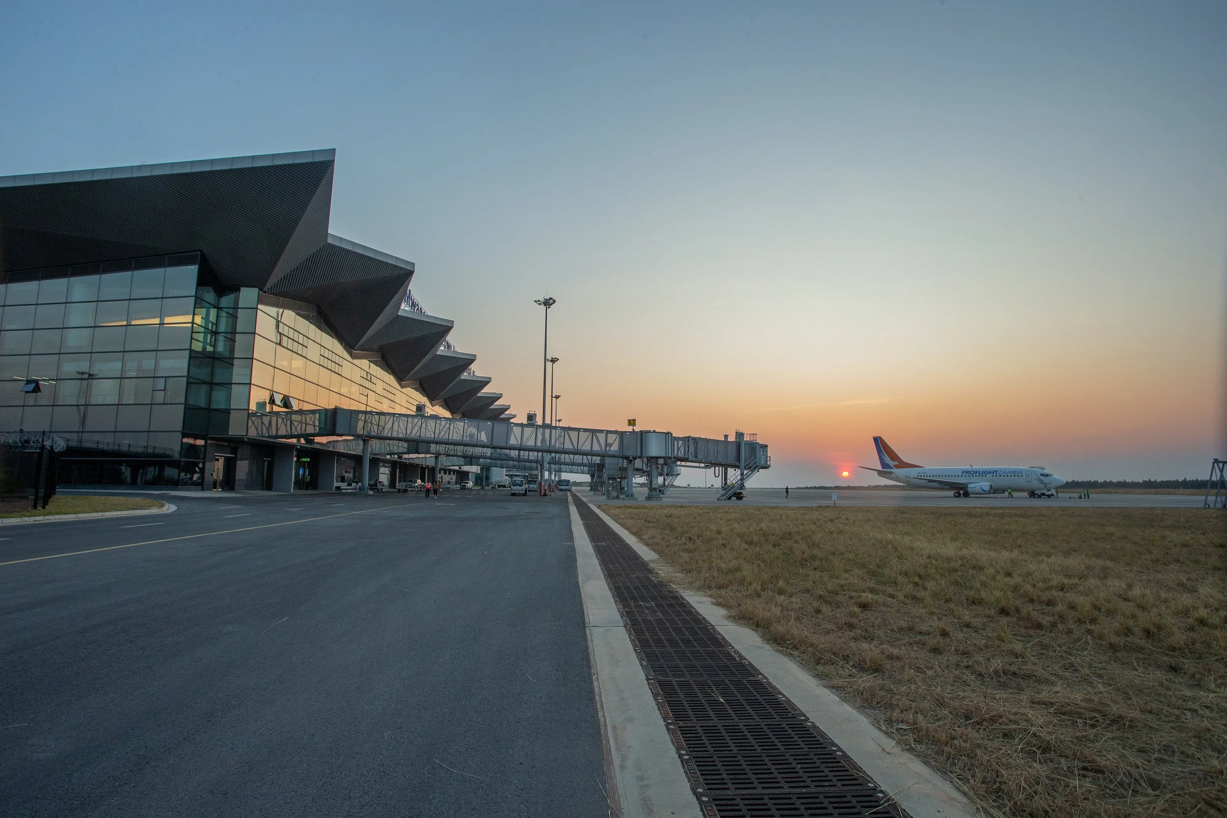Airport terminal with airplane taxiing on the runway at sunset.