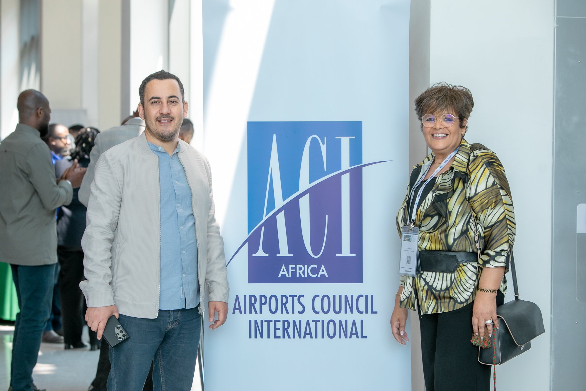 A man and a woman standing in front of a sign that reads 'ACI Africa Airports Council International' at what appears to be a conference or event.