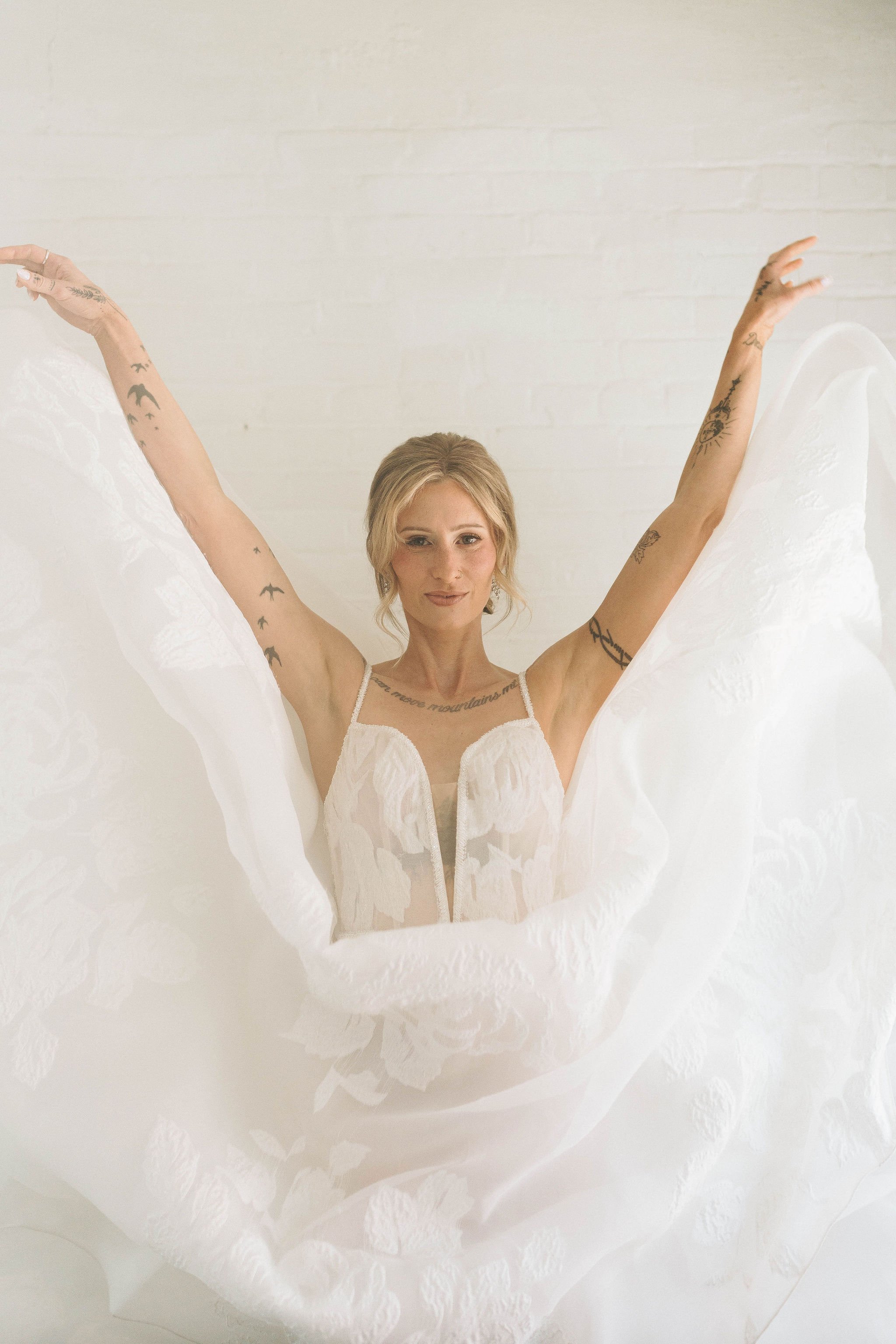bride lifting her arms high as she releases her long white dress train and it flows down