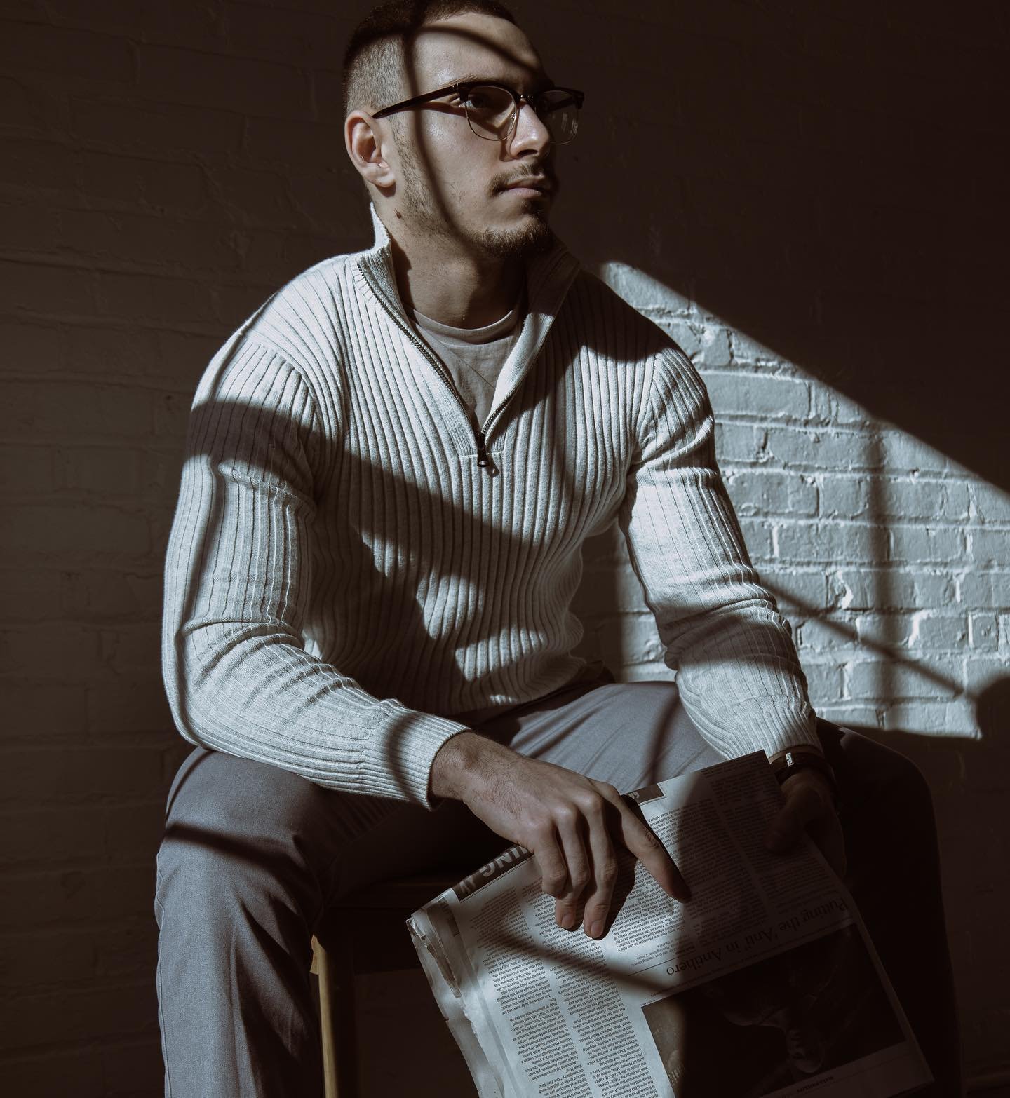 light streaming in window of very dark space with guy sitting and looking off into the distance