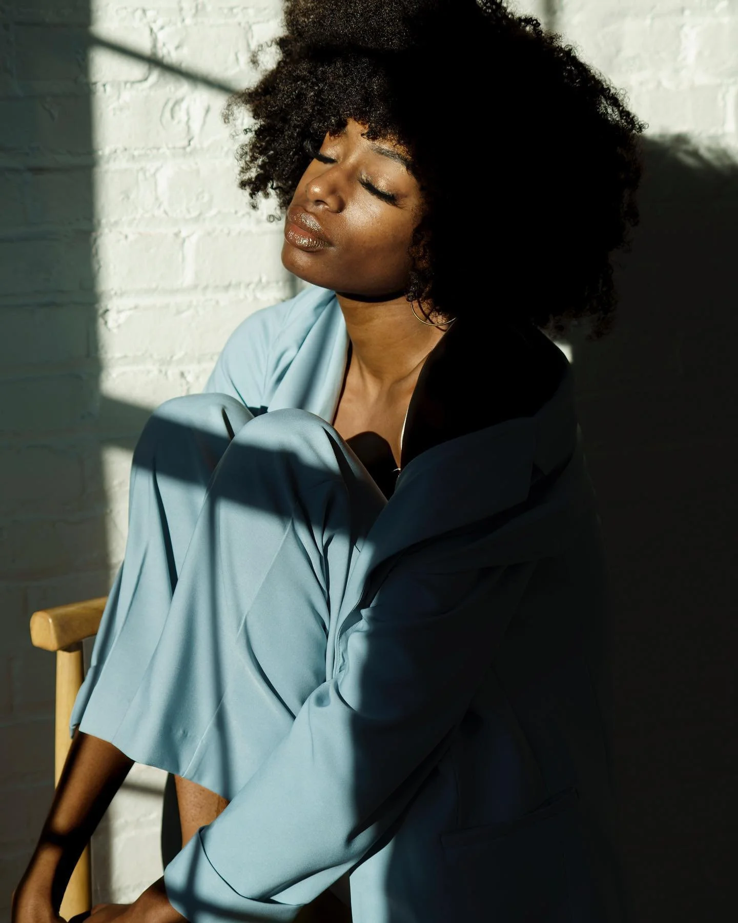 bright sunlight streaming in window and hitting woman's face as she angles toward the light