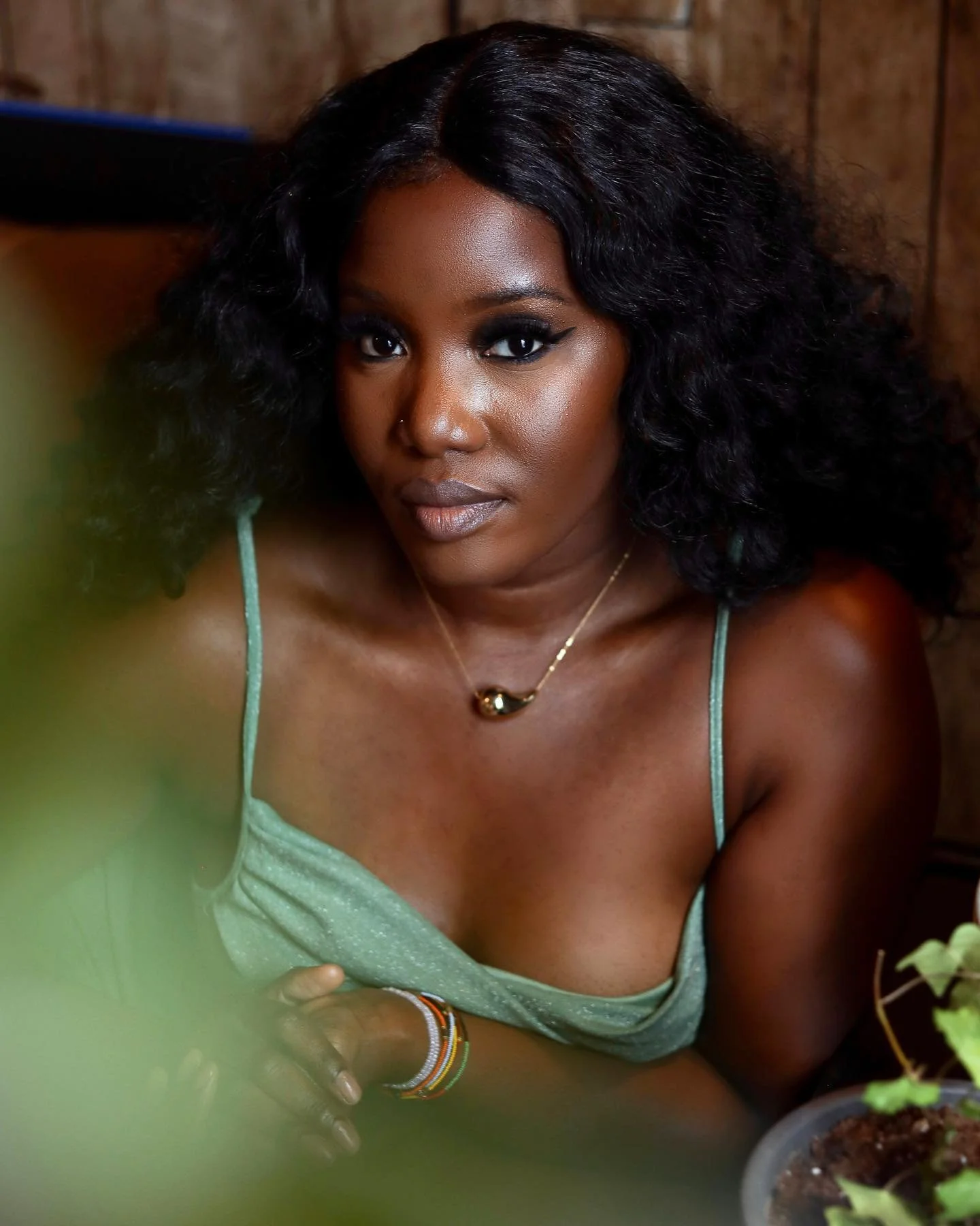 close up photo of woman in green dress staring at the camera and barely smiling