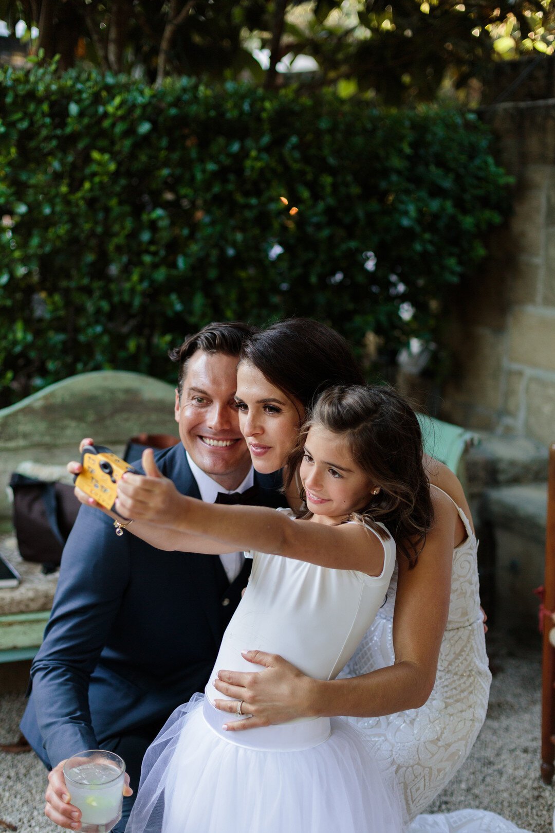 www.santabarbarawedding.com | Kaitie Brainerd | San Ysidro Ranch | Indochino | Blush by Hayley Paige | Bride and Groom Take a Picture with Flower Girl 