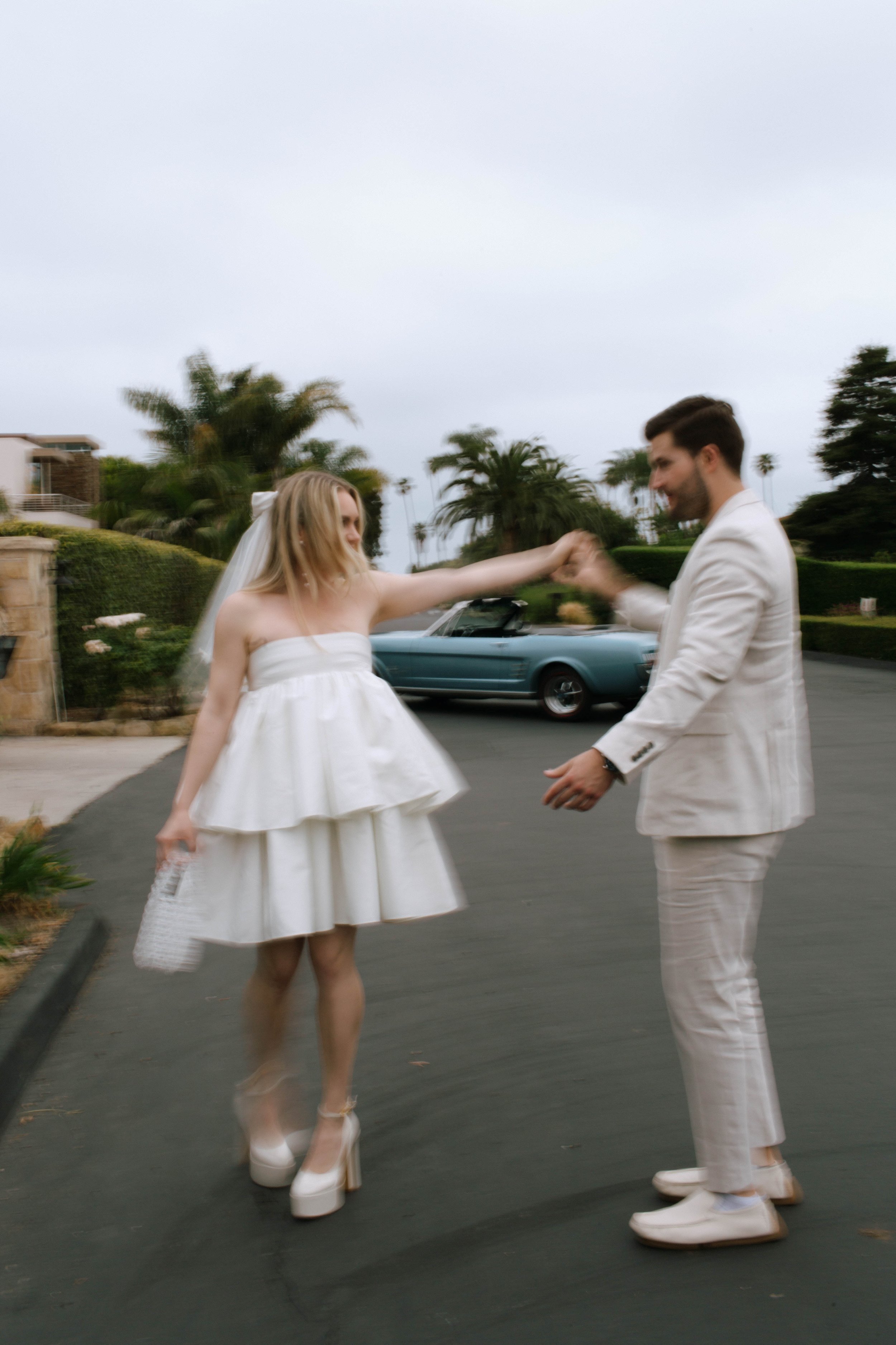 www.santabarbarawedding.com | Monique Bianca Photography | Downtown Santa Barbara | Valentino | Rotate | Couple Twirling In Front of a Blue Convertible