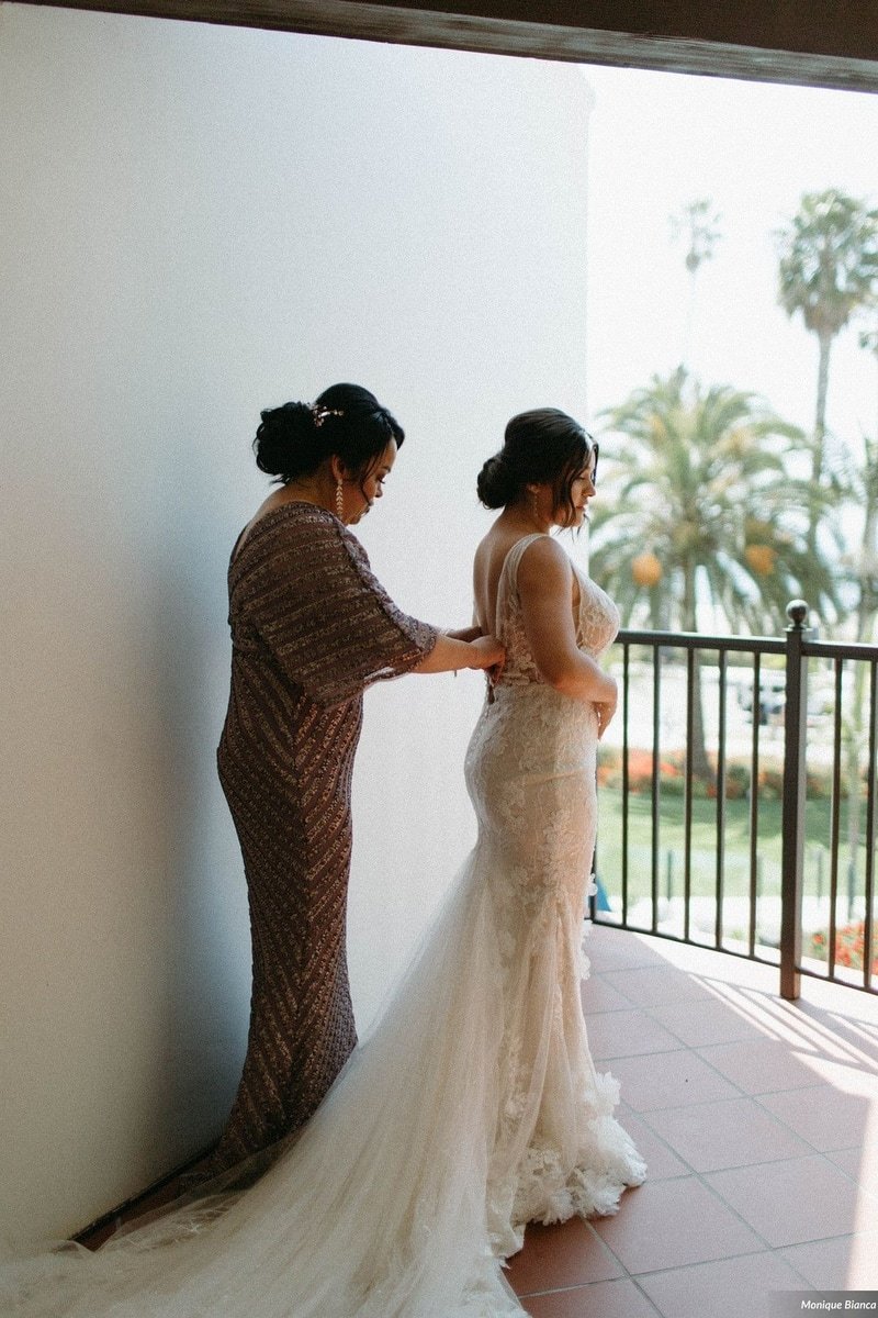 www.santabarbarawedding.com | Our Lady of Mount Carmel | Monique Bianca | White Sage | Intrepid Floral Co. | Enzoani | Bride Putting on Her Dress