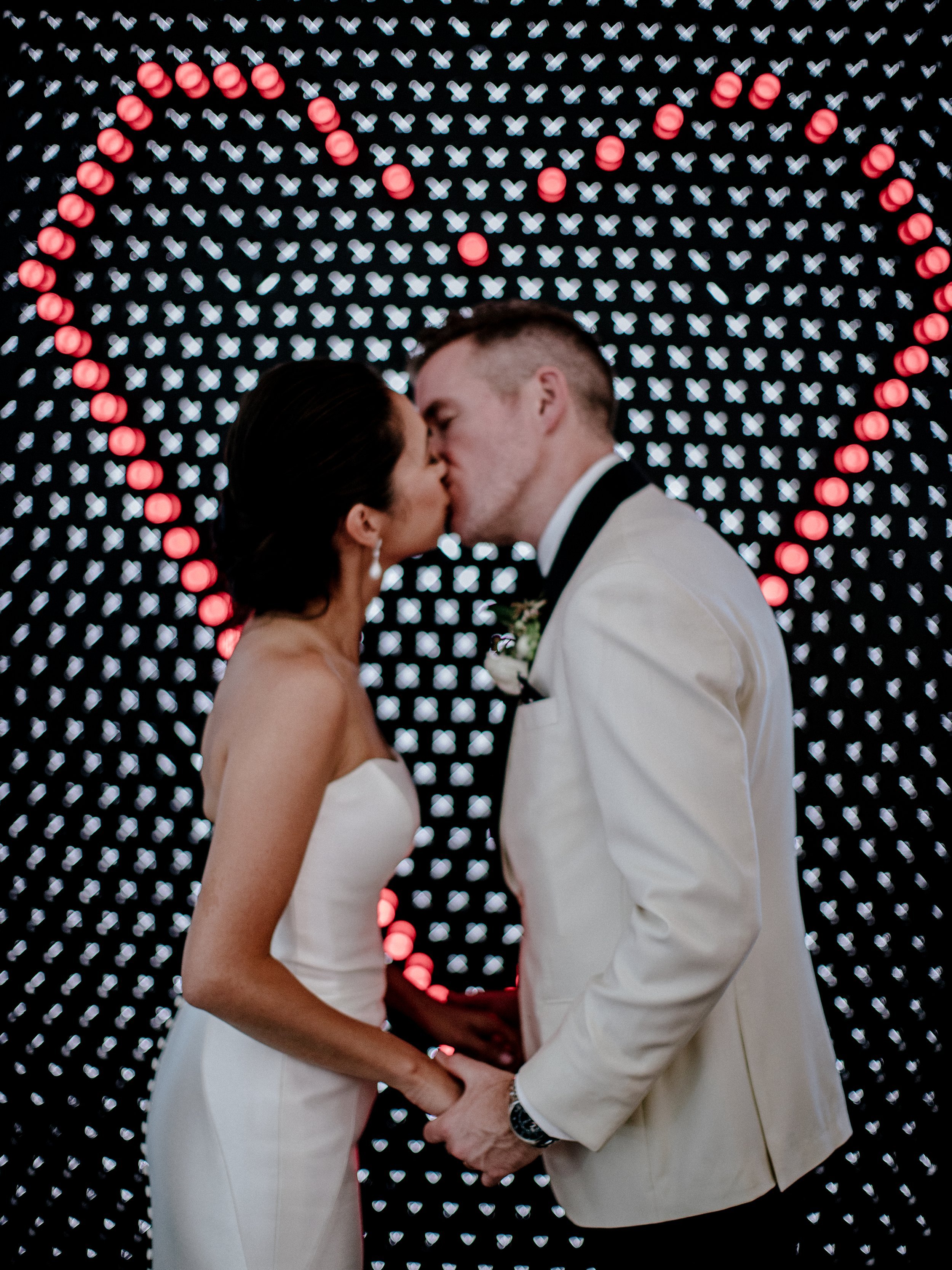 www.santabarbarawedding.com | Chris J. Evans | MOXI Museum | Tyler Speier Events | TEAM Hair &amp; Makeup | Pronovias | The Black Tux | Couple Kissing in Front of Illuminated Heart