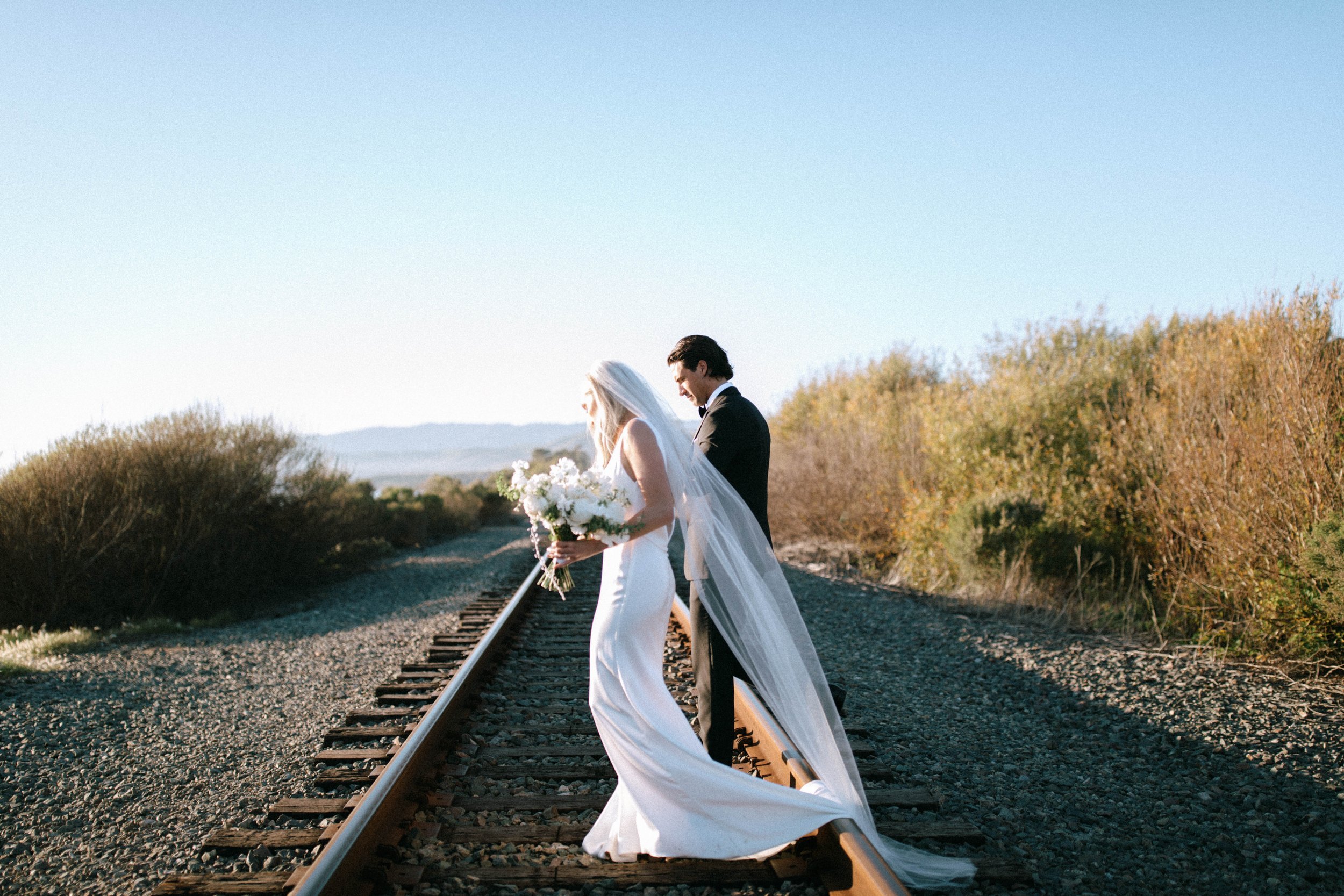 www.santabarbarawedding.com | Monique Biance | Amazing Days Events | Dos Pueblos Orchid Farm | Studio Fleurish | Pretty Please Beauty | Flora Bridal | The Dress Theory | Couple Walking on Tracks