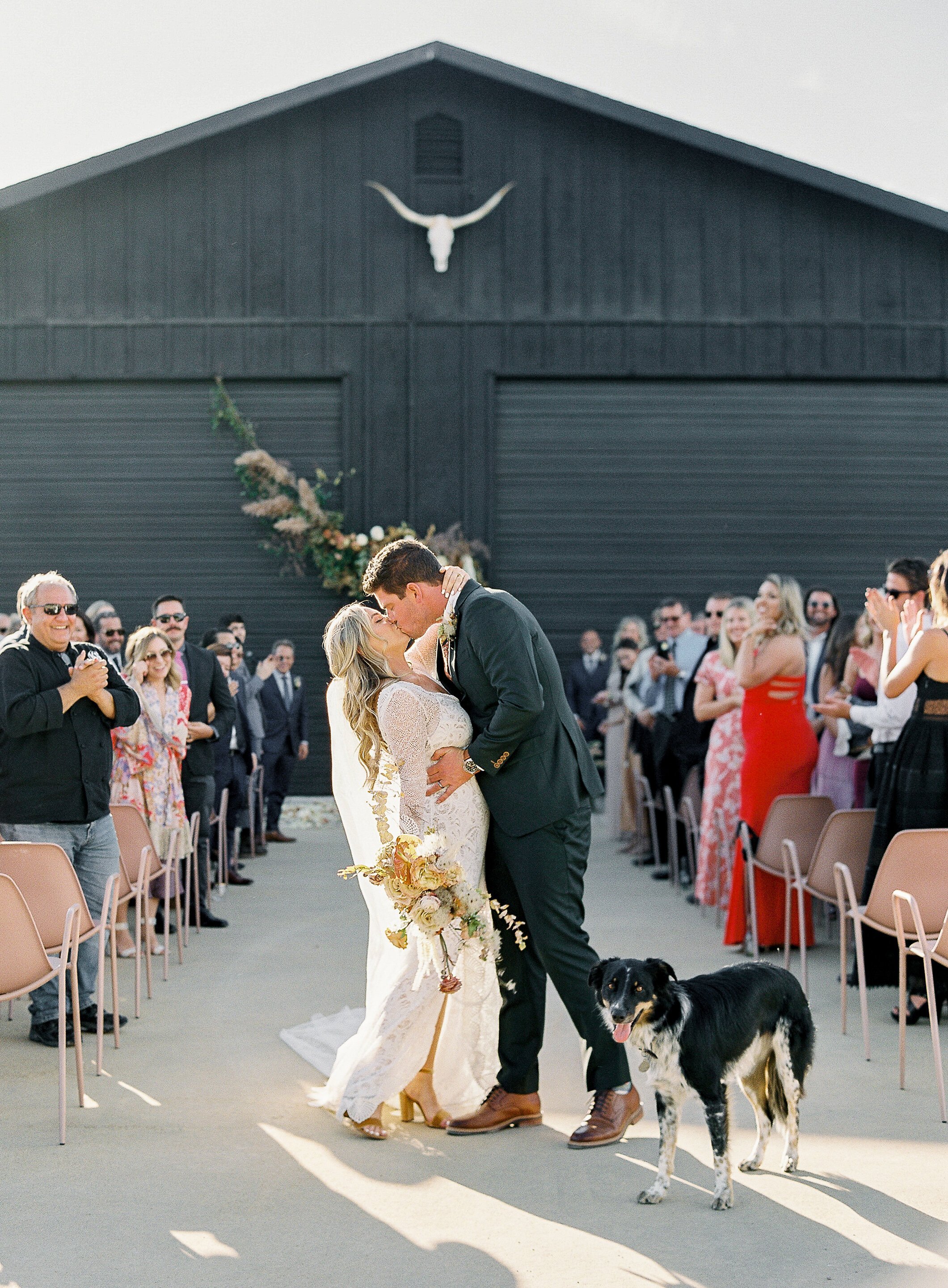 www.santabarbarawedding.com | Sposto Photography | Bride and Groom Kissing at Ceremony with Dog at Their Side  