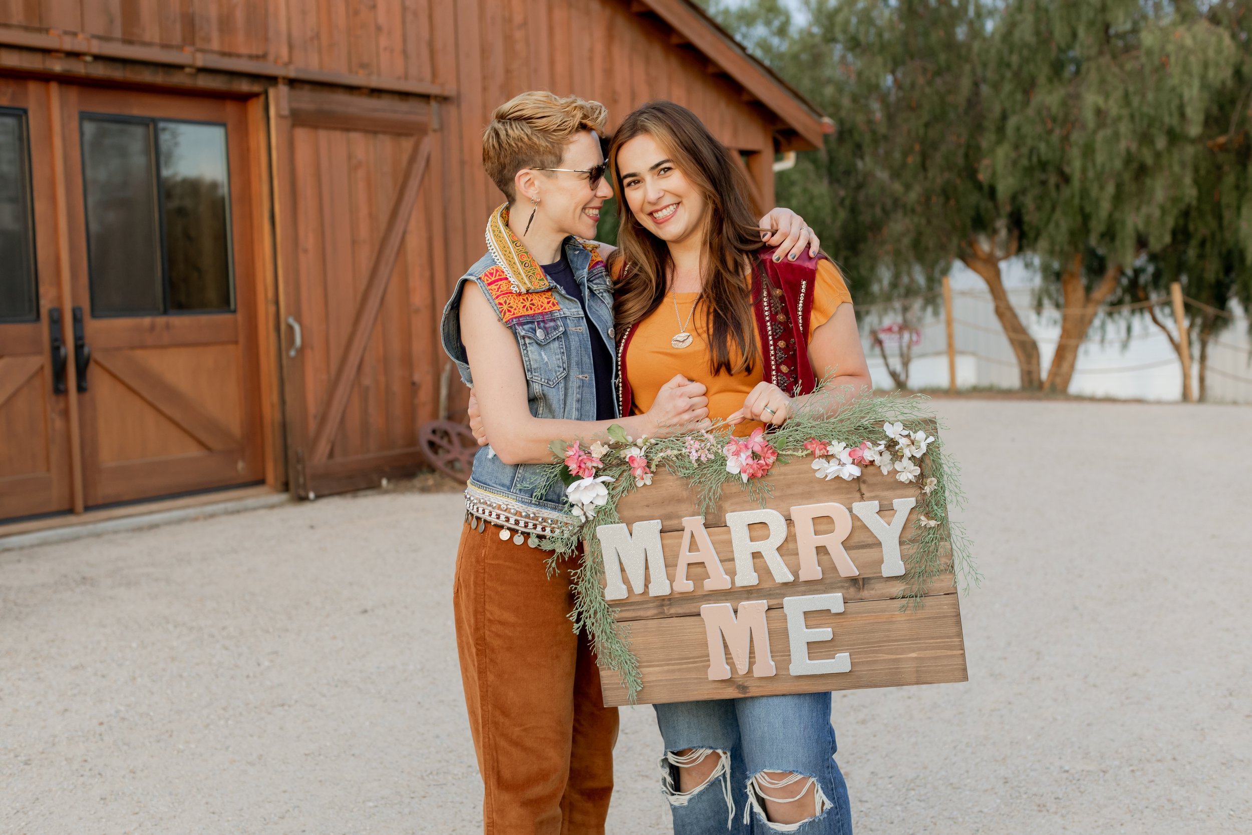 www.santabarbarawedding.com | MacKenzie Rana Photography | Fish House San Luis Obispo | Couple Embracing and Holding Marry Me Sign at Engagement Shoot