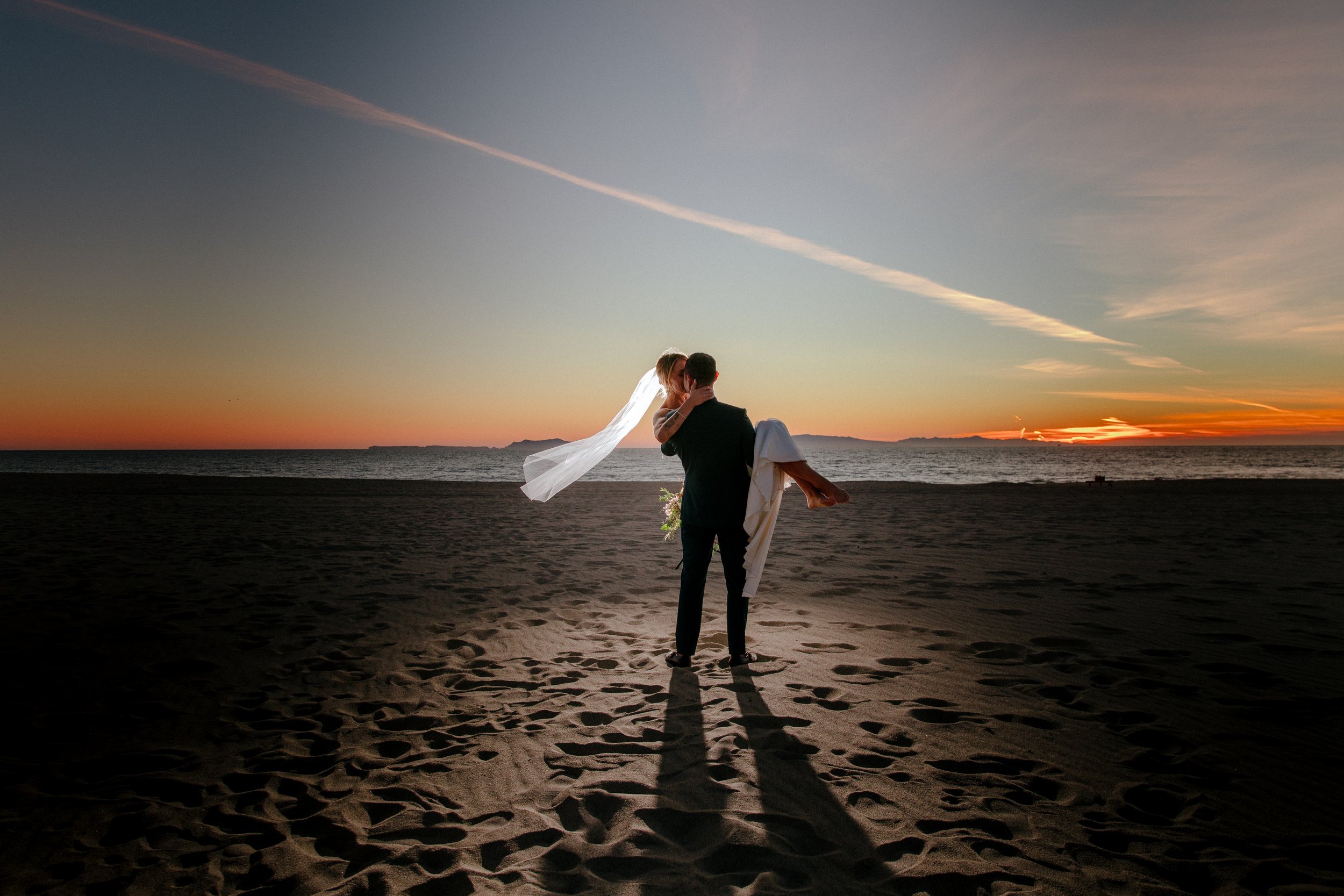www.santabarbarawedding.com | Chris J. Evans | Paul Smith Suit | Groom Holding His Bride on the Beach at Sunset