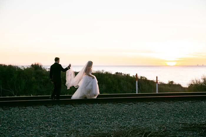 www.santabarbarawedding.com | Soigne Productions | Dos Pueblos Orchid Farm | Miki and Sonja | LunaBella | Bride and Groom on the Railroad Tracks by the Ocean