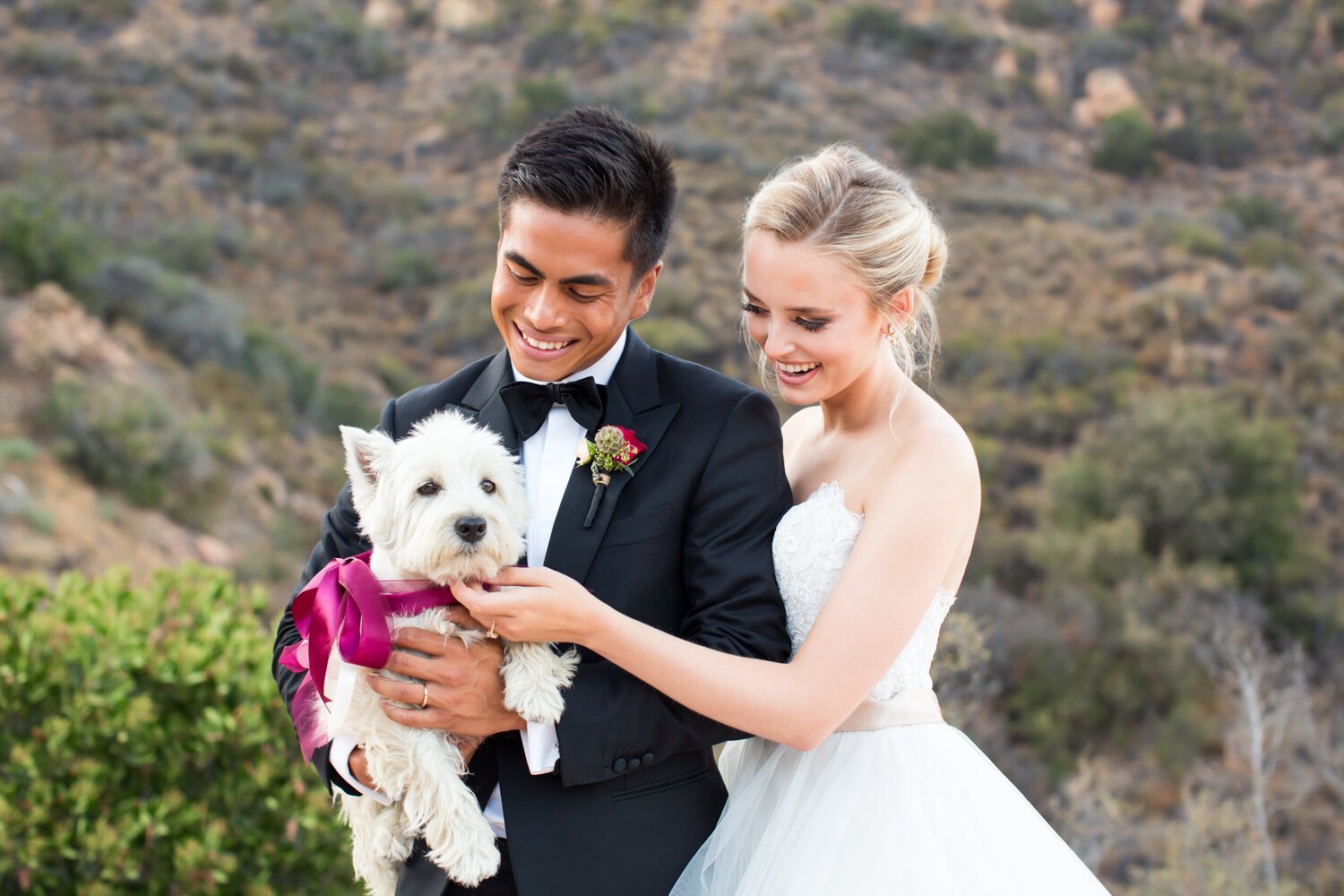 www.santabarbarawedding.com | Elizabeth Victoria Photography | Ebeling Events | APEX Malibu | Couple Holding a White Puppy with Magenta Ribbon 
