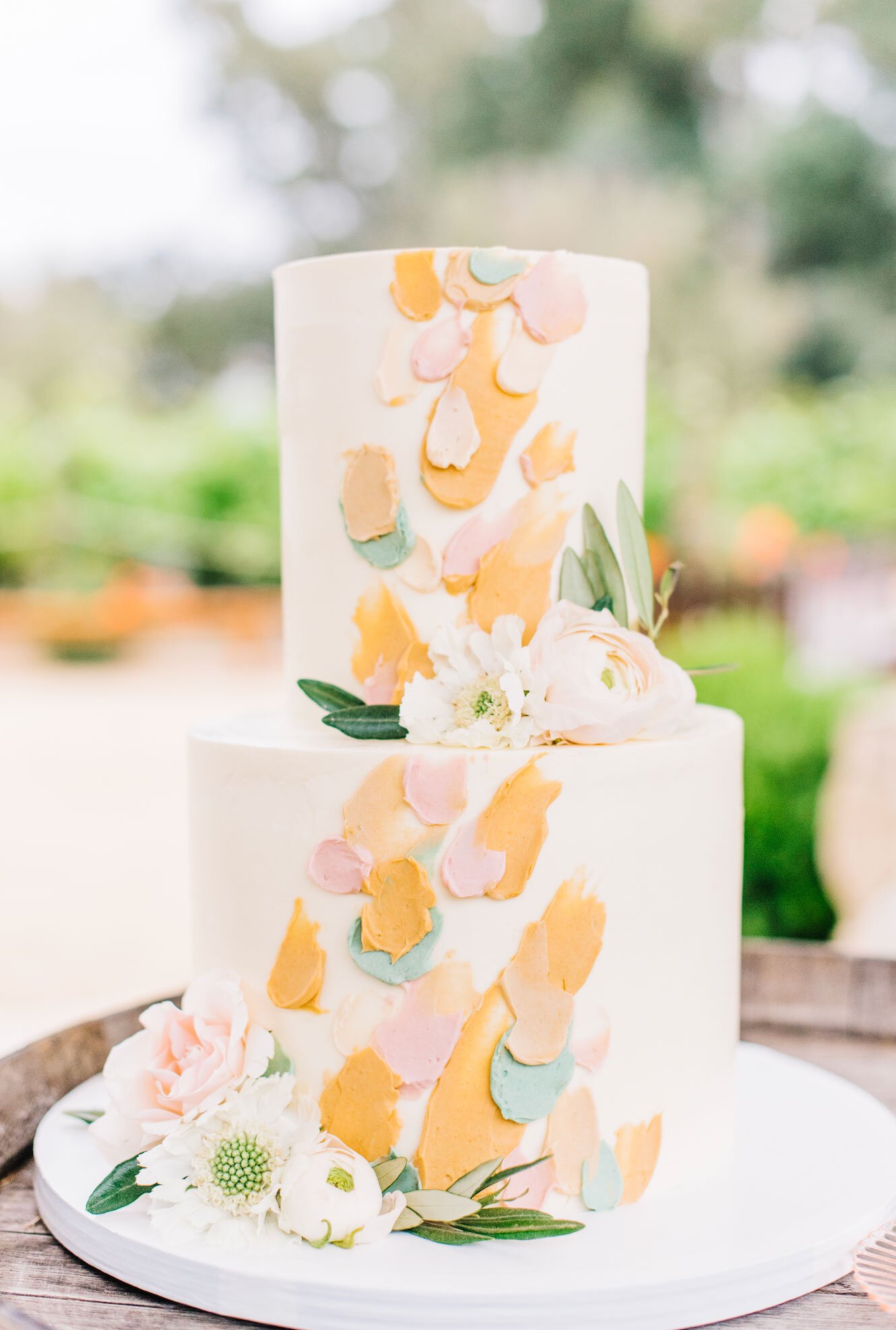 www.santabarbarawedding.com | White Sage | Topa Mountain Winery | Cara Robbins Studios | Olivetta Flowers | Lilac Patisserie | Two Tiered White Wedding Cake with Orange, Pink, and Blue Details