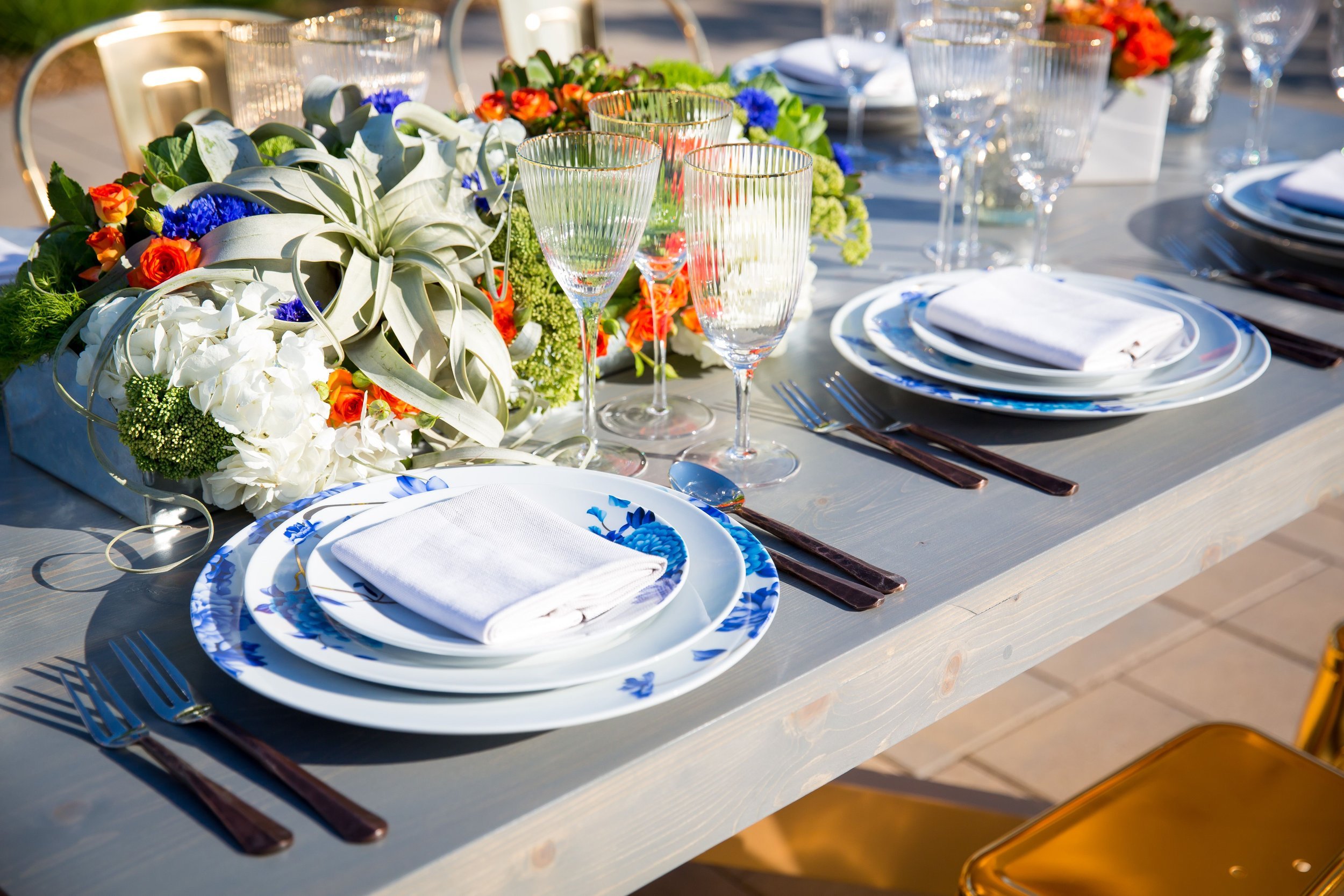 www.santabarbarawedding.com | Bright Event Rentals | Vanity Portrait Studio | Place Setting with Blue and White Plates, Crystal Glassware, Wood and Silver Flatware, and Flower Centerpieces