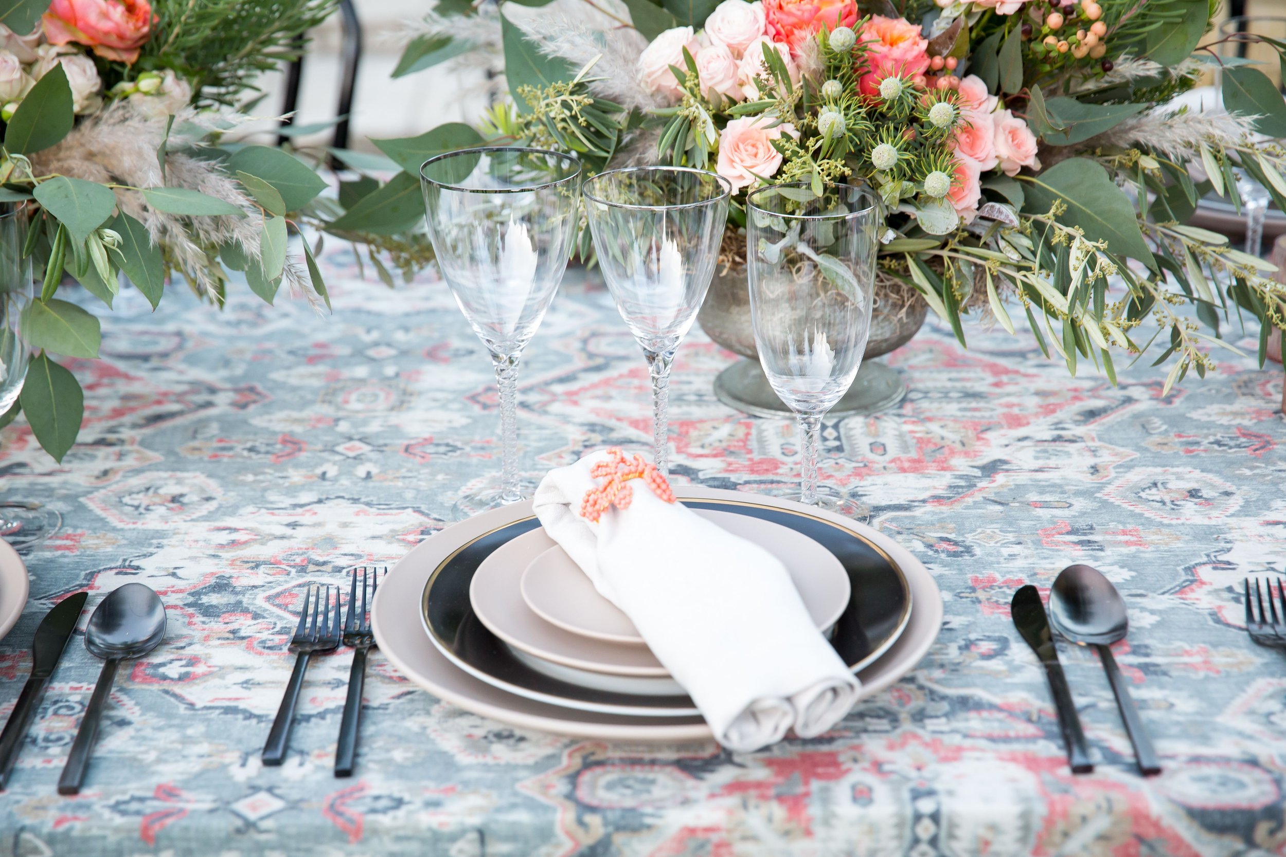 www.santabarbarawedding.com | Bright Event Rentals | Vanity Portrait Studio | Place Setting with Black and White Plates and Black Silverware on a Patterned Tablecloth
