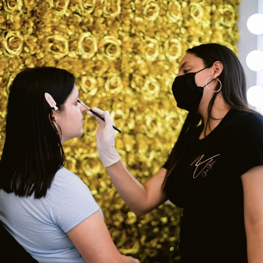 www.santabarbarawedding.com | NV Glam Studio | Makeup Artist Completing Makeup for the Bride with a Background Wall of Yellow Flowers 