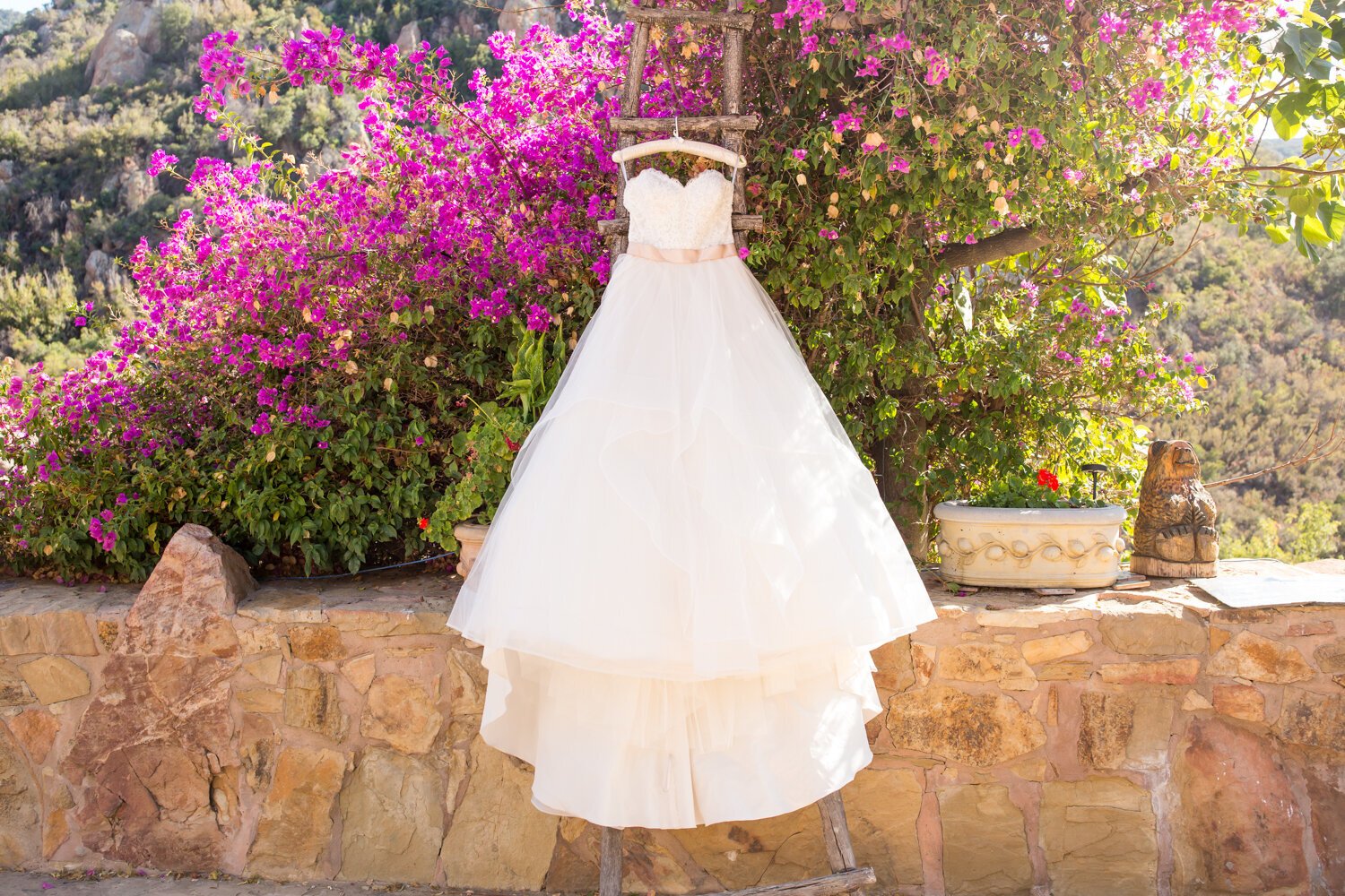 www.santabarbarawedding.com | Elizabeth Victoria Photography | Ballgown Wedding Dress Hanging Against a Wall of Bright Pink Flowers 