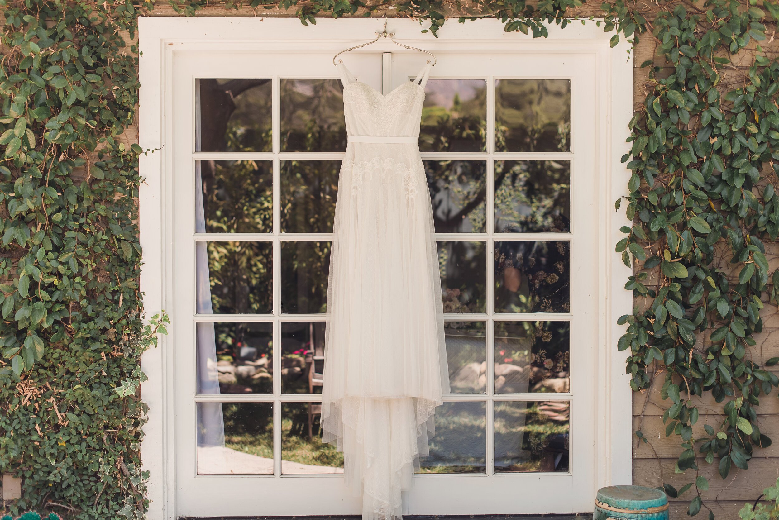 www.santabarbarawedding.com | Sun &amp; Sparrow Photography | Modern Wedding Gown Hanging Against Window and Wall with Ivy 