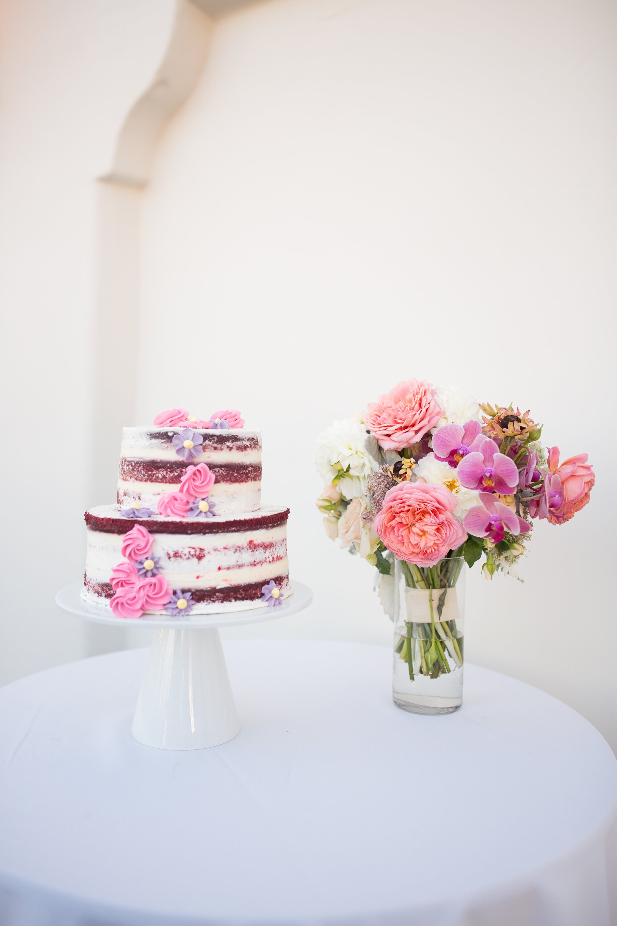 www.santabarbarawedding.com | Kelsey Crews Photo | Ritz-Carlton Bacara | Ella &amp; Louie | Naked Wedding Cake and Vase of Pink and Purple Flowers