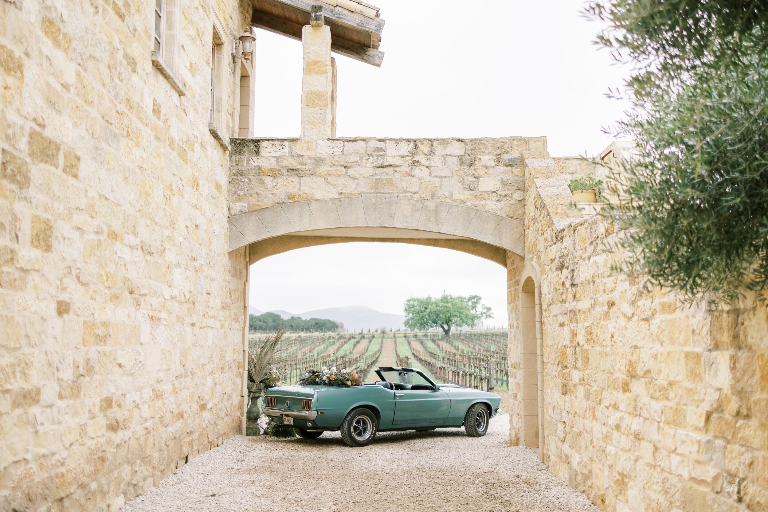 www.santabarbarawedding.com | Jocelyn &amp; Spencer | Sunstone Winery | Styled Shoots Across America | Redempta Rentals | PineStreet Floral | Vintage Blue Mustang Under Sunstone Arch 