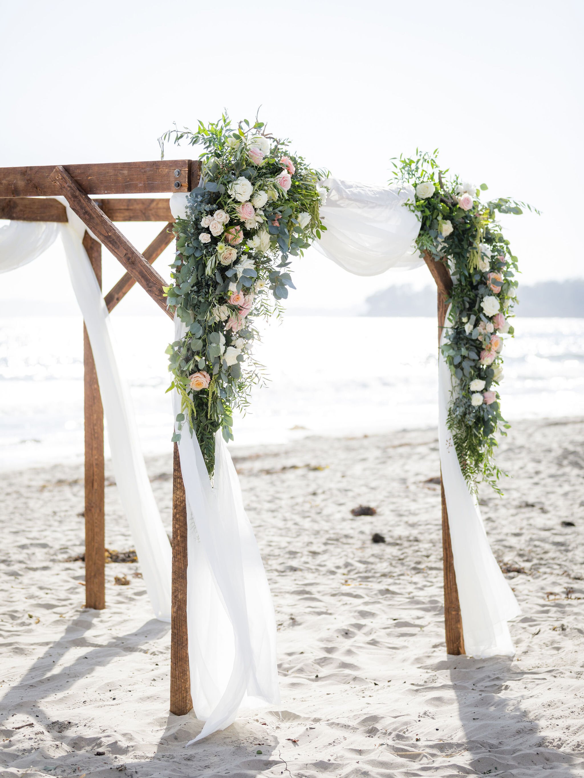 www.santabarbarawedding.com | Head &amp; Heart Photography | Rincon Beach Club | Events by Rincon | The Twisted Twig | The Wedding Arch with Flowers and White Drapery on the Beach