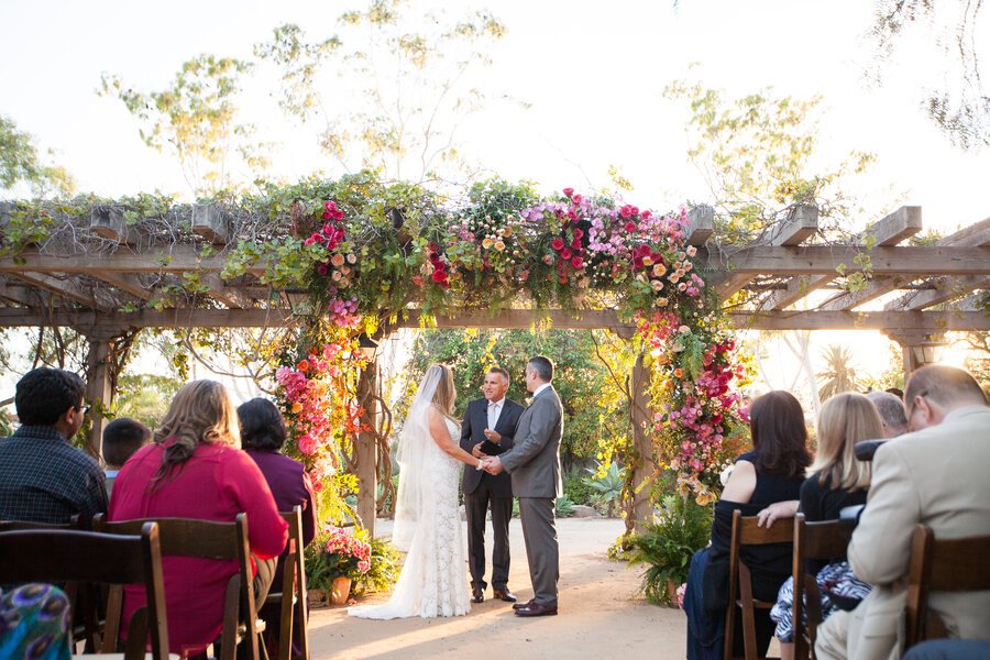 www.santabarbarawedding.com | Santa Barbara Historical Museum | Nicole Caldwell Studio | Adobe Courtyard Wedding Ceremony with Light and Dark Pink Flowers on the Wedding Arbor