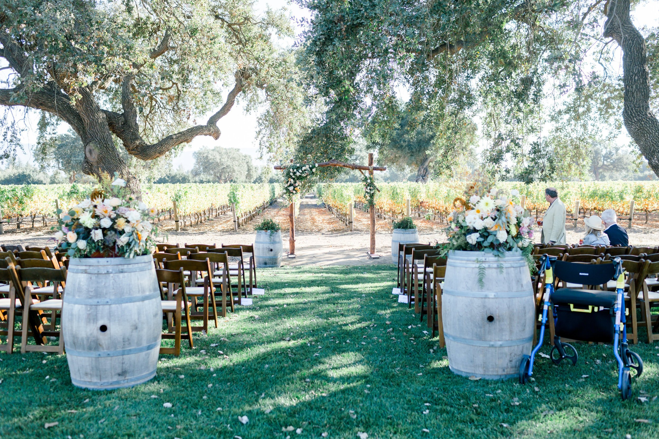 www.santabarbarawedding.com | Aura Elizabeth Photo | Margaret Joan Floral | Ceremony Aisle wiht Wooden Chairs and Barrels with Flowers at the Entrance
