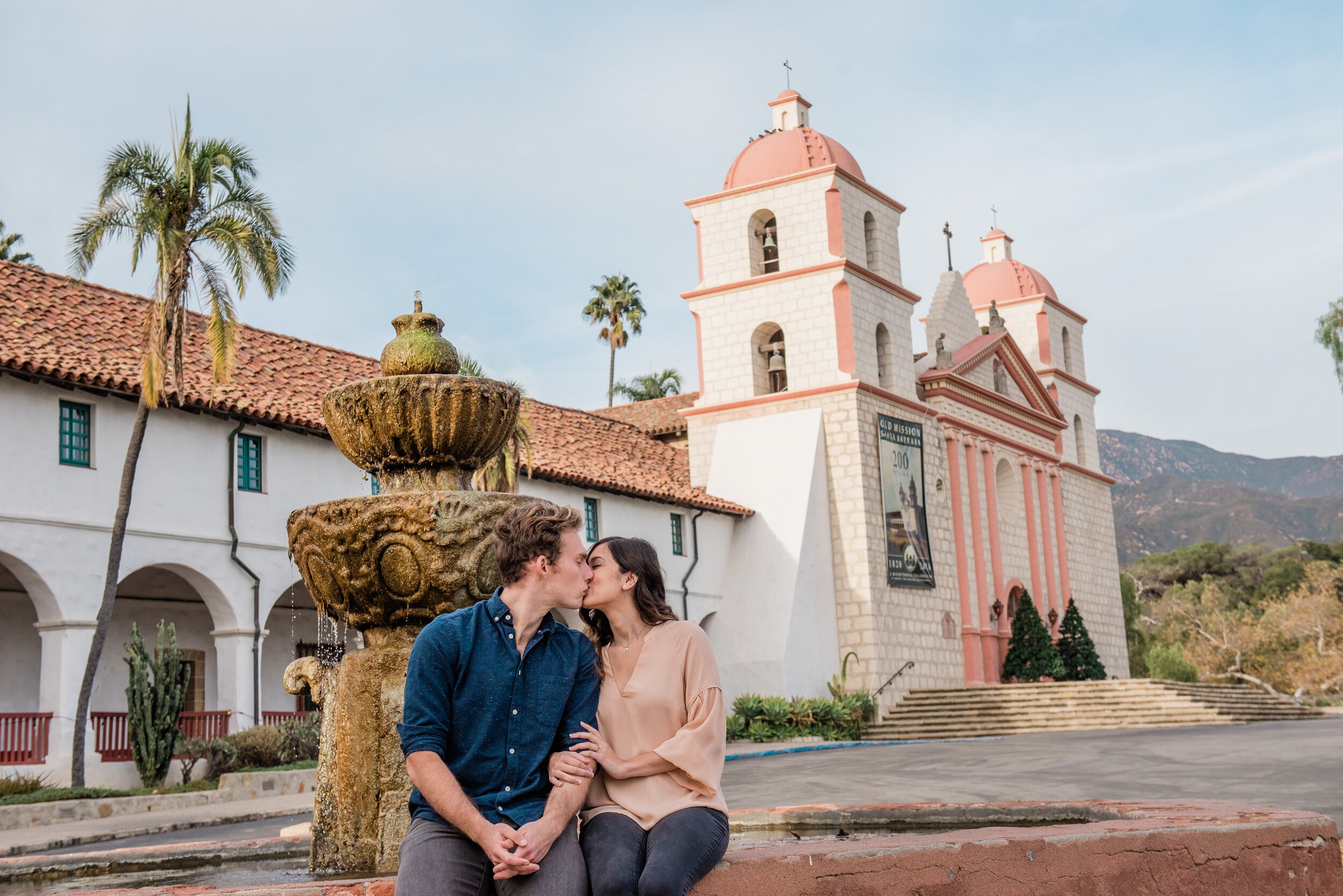 www.santabarbarawedding.com | ByCherry Photography | Old Mission Santa Barbara | Couple Kisses with the Pink Old Mission Building in the Background
