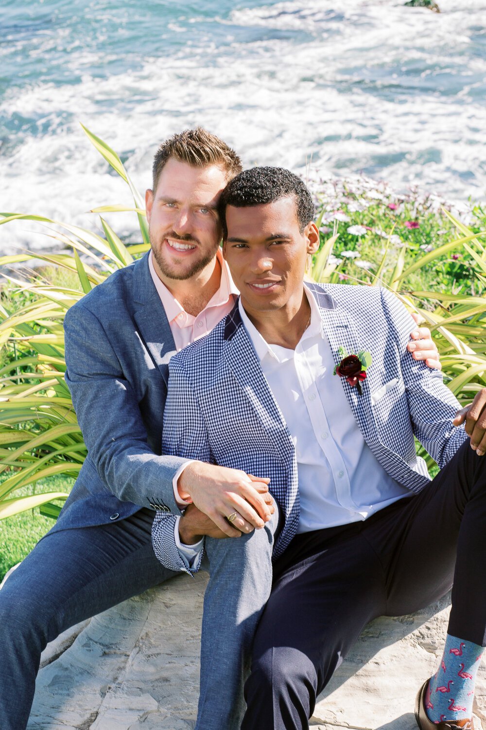 www.santabarbarawedding.com | Renoda Campbell Photography | Renoda Campbell Events | Flourish Event &amp; Floral Design | Men’s Wearhouse | Grooms Embrace on a Rock in Front of the Ocean