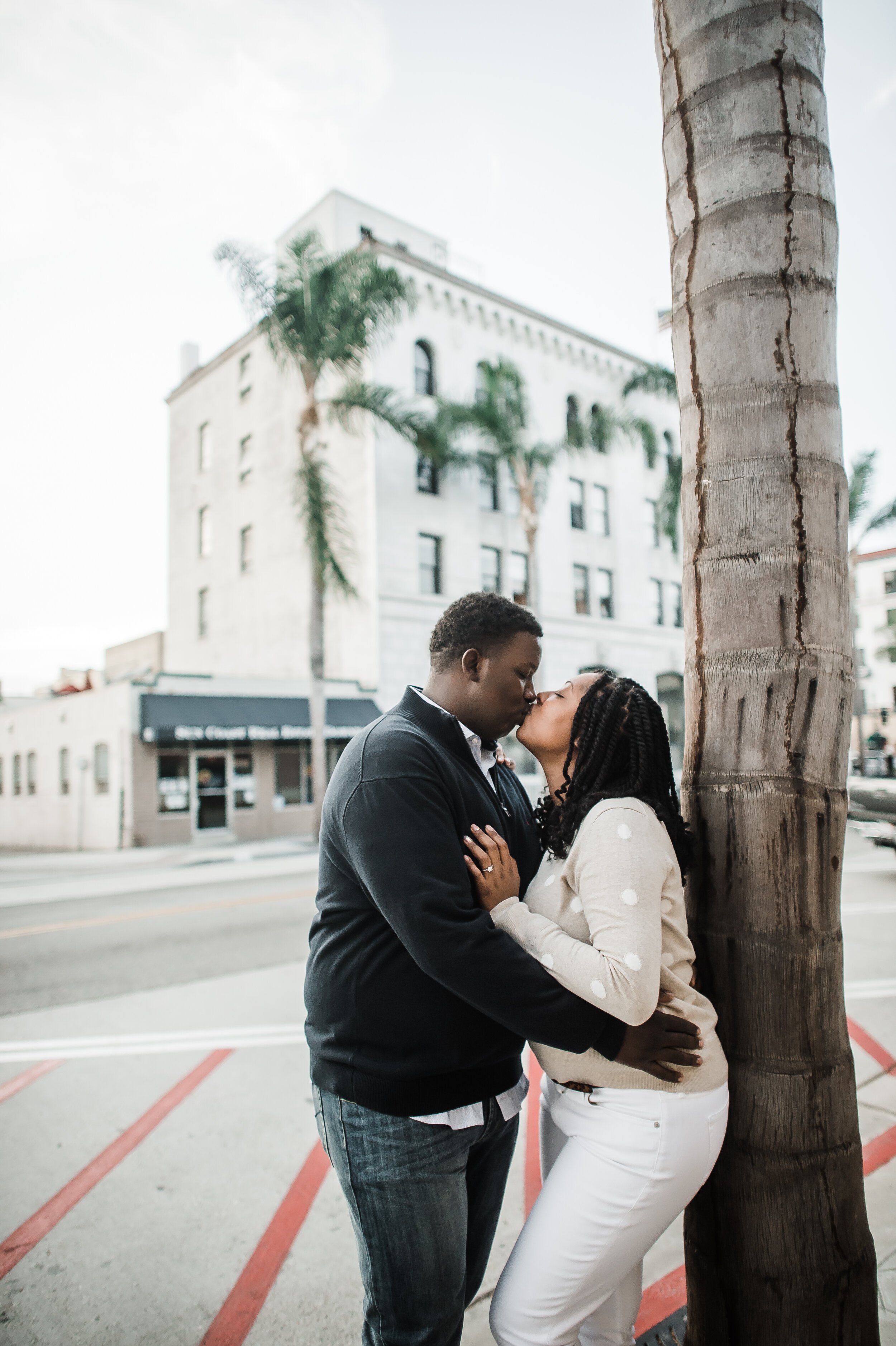www.santabarbarawedding.com | Michelle Ramirez Photography | Couple Kisses by A Palm Tree in Downtown Ventura During Engagement Session