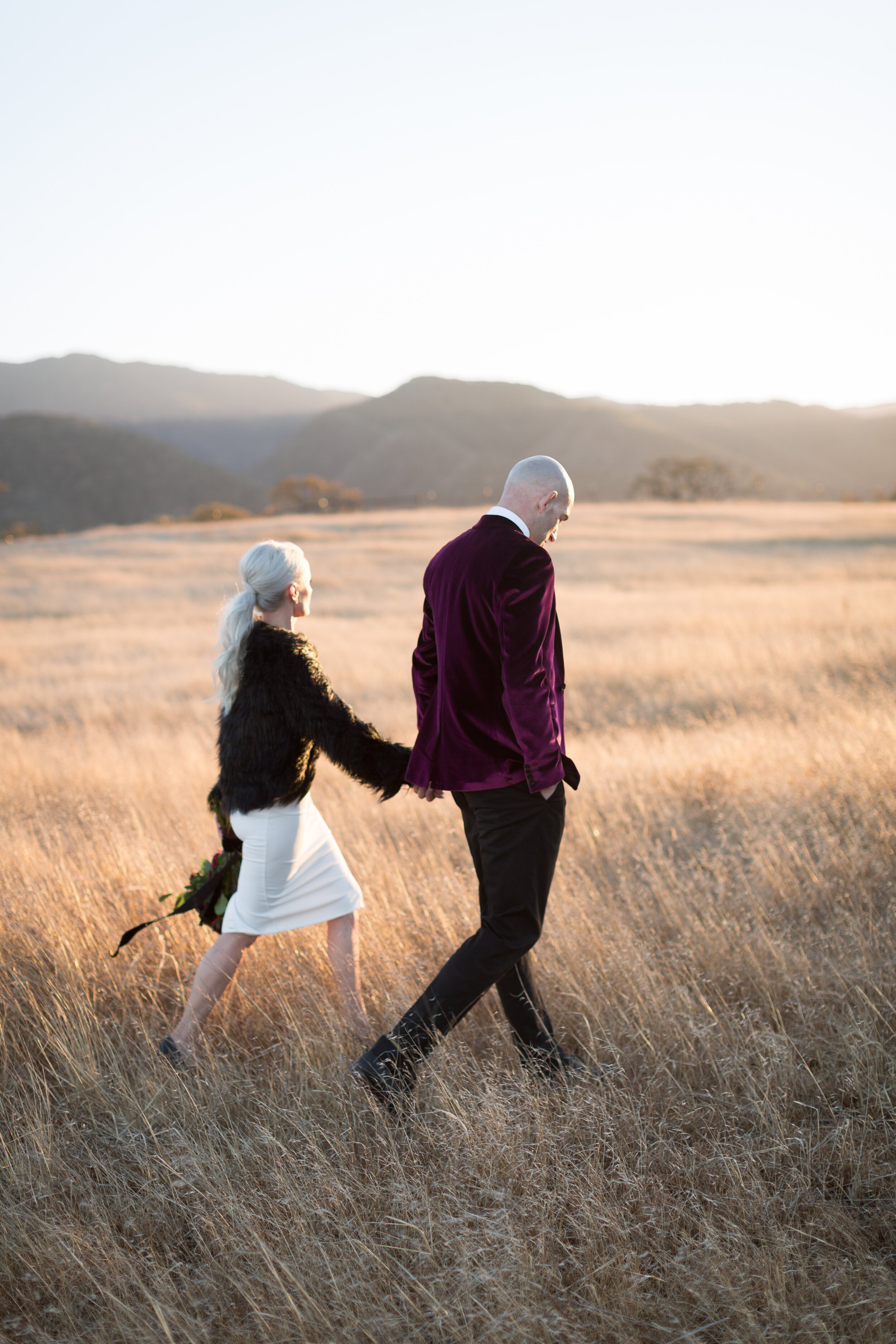 www.santabarbarawedding.com | Kestrel Park | Kiel Rucker | Armando of Santa Barbara Elopement | Grossi Florist | Bride and Groom Walking in the Field at Sunset