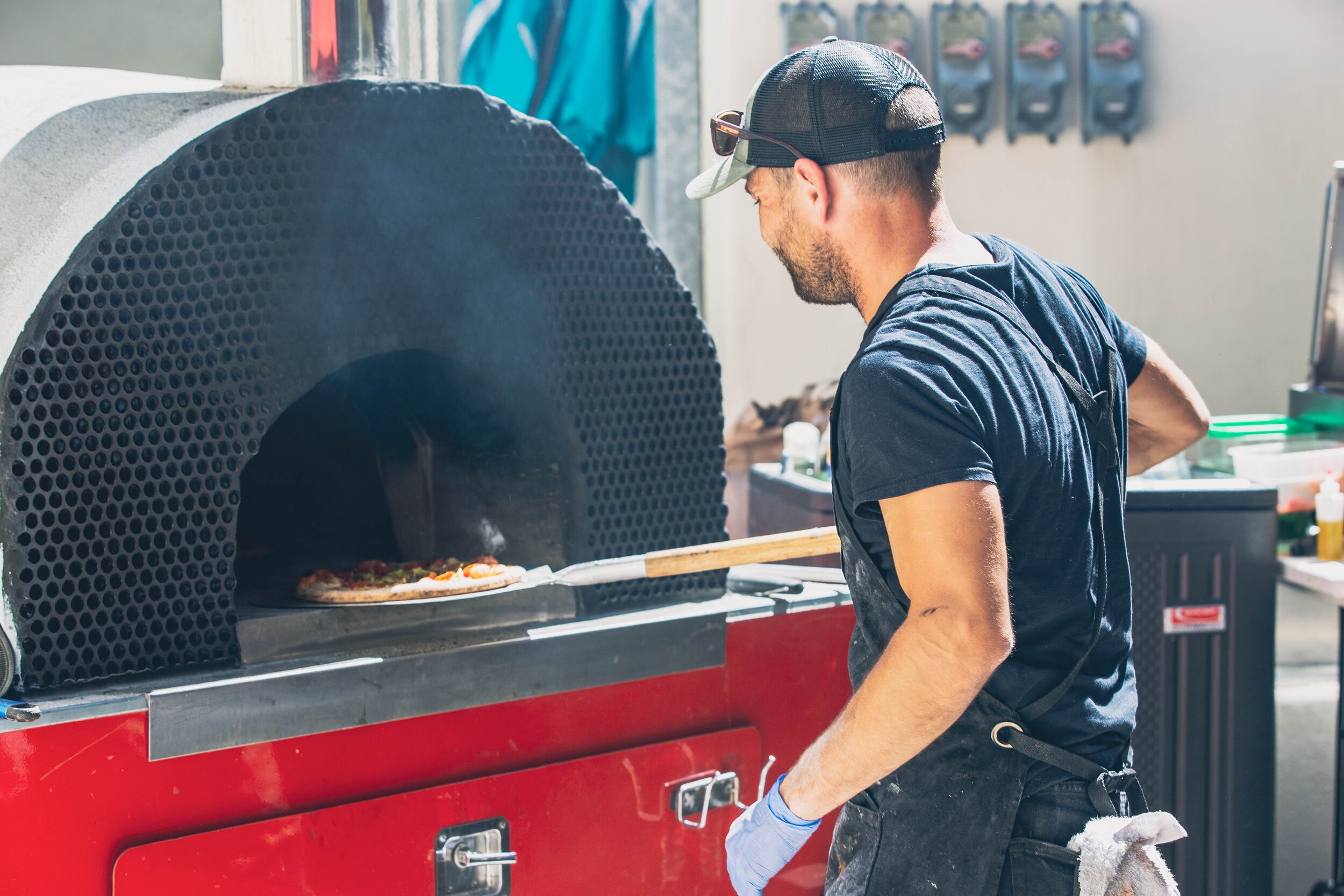 www.santabarawedding.com | Firefly Pizza Company | Putting Pizzas in the Wood Fire Oven